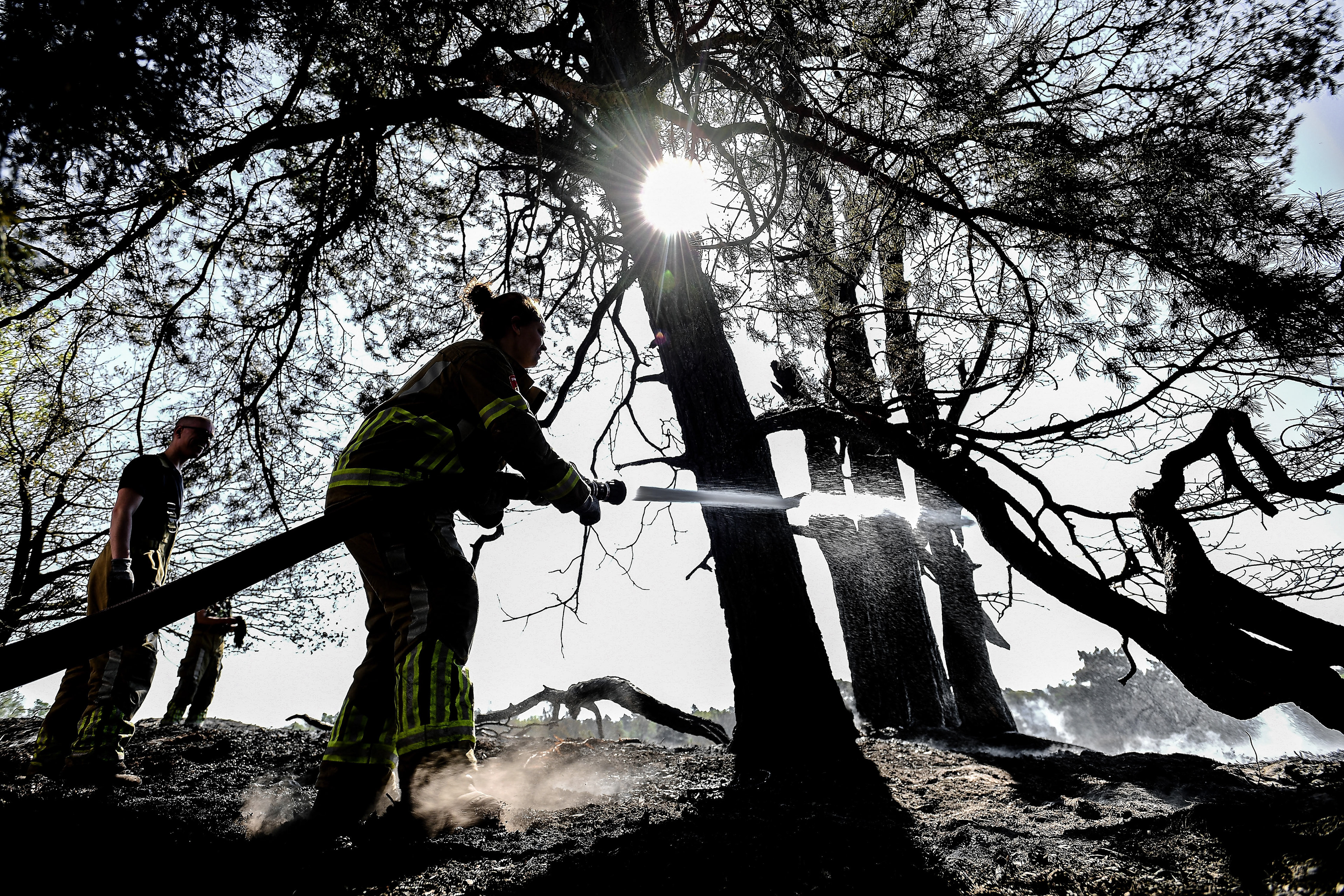 Firefighters extinguish a source of fire on the third day of a forest fire at the national park De Meinweg in the German-Dutch border area near Niederkruechten, Germany, 22 April 2020. (Photo by Sascha Steinbach/epa)