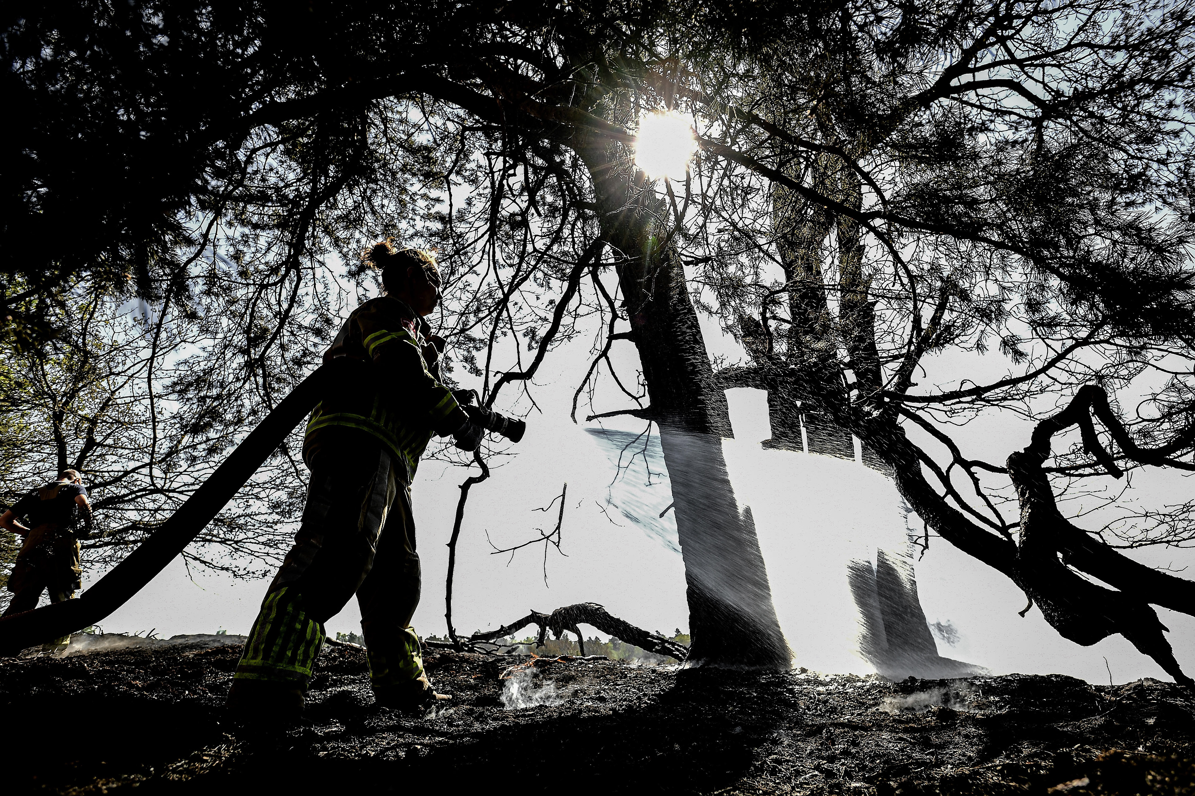 Firefighters extinguish a source of fire on the third day of a forest fire at the national park De Meinweg in the German-Dutch border area near Niederkruechten, Germany, 22 April 2020. (Photo by Sascha Steinbach/epa)