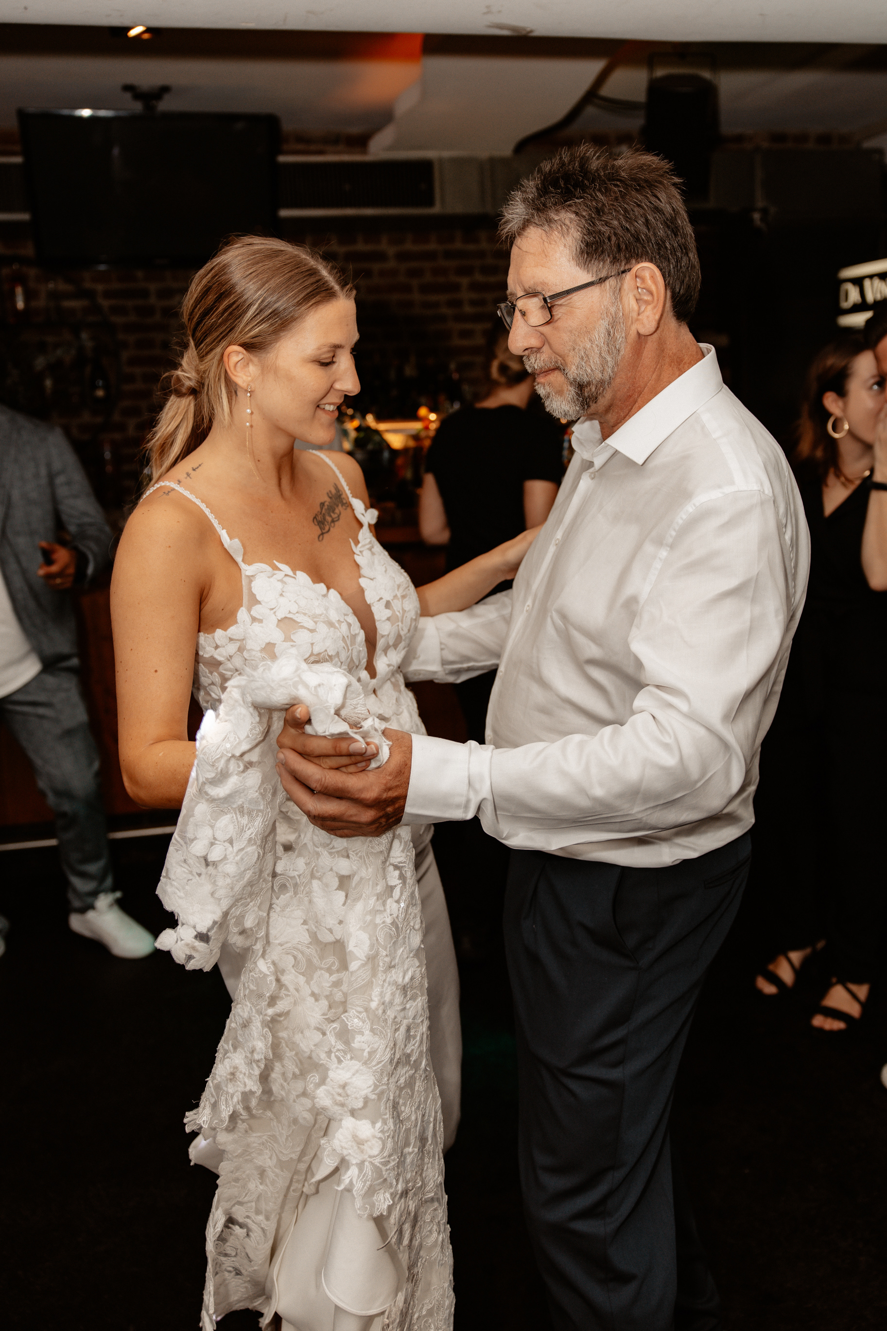 Die Braut und der Vater des Brätigam tanzen miteinander auf der Hochzeit, während sie sich lächelnd ansehen. Eine emotionale-Momentaufnahme auf der Tanzfläche.