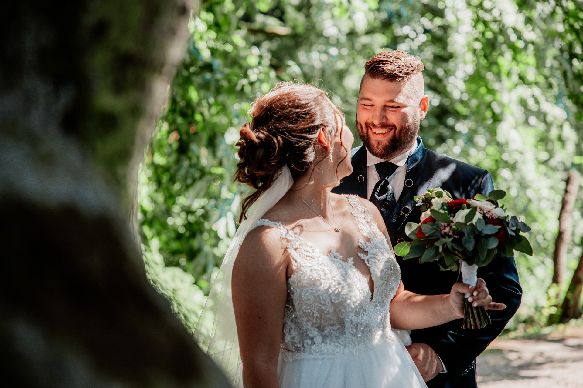 Denise und Michael lachen einander an, während sie sich liebevoll im Park umarmen ein unvergesslicher Hochzeitsmoment.