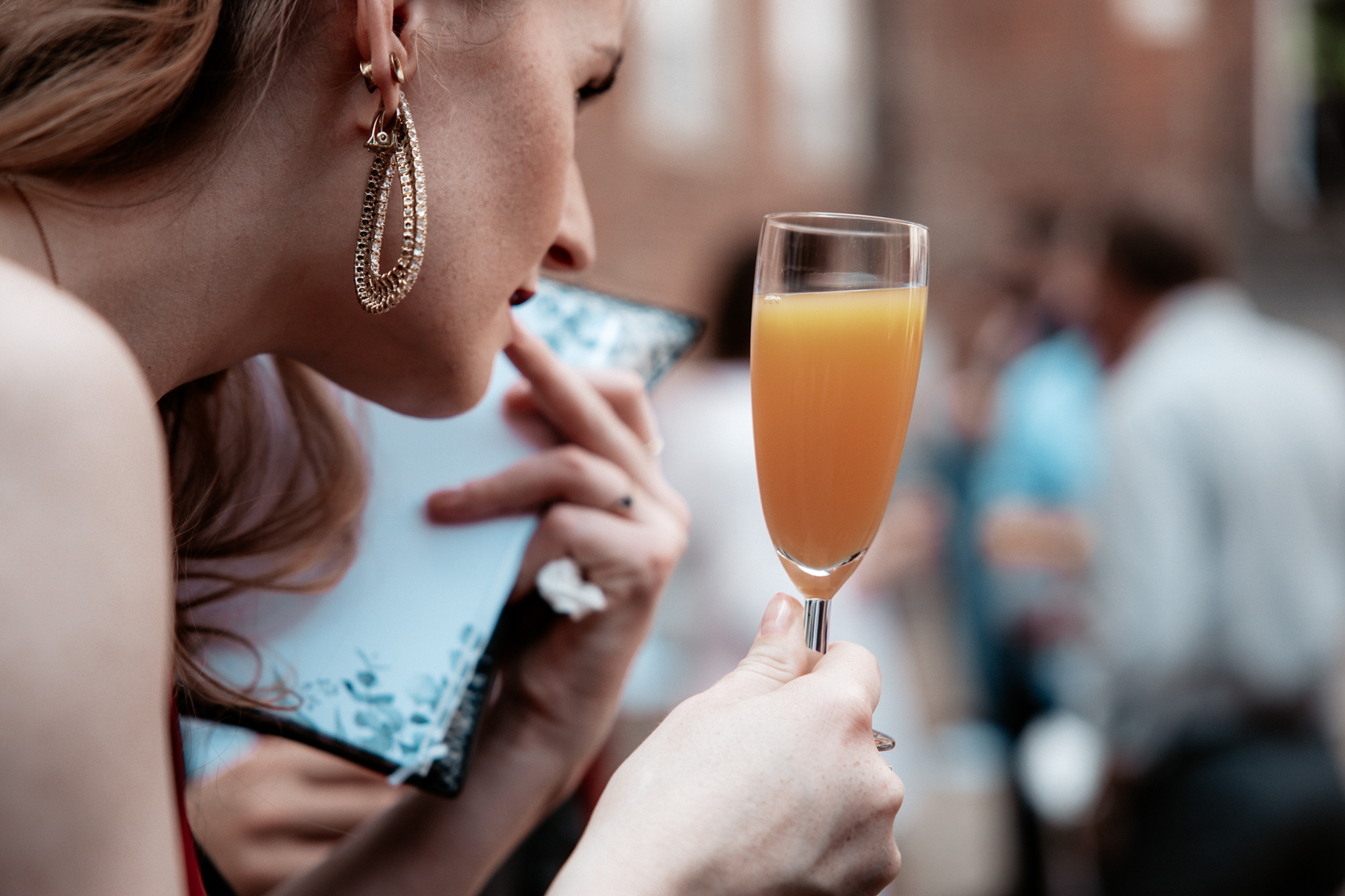 Hochzeitsfeier von Christina & Phillip – Nahaufnahme einer Hochzeitsgästen mit einem Glas Orangensaft während des Empfangs. Hochzeitsreportage mit Liebe zum Detail in Herten.