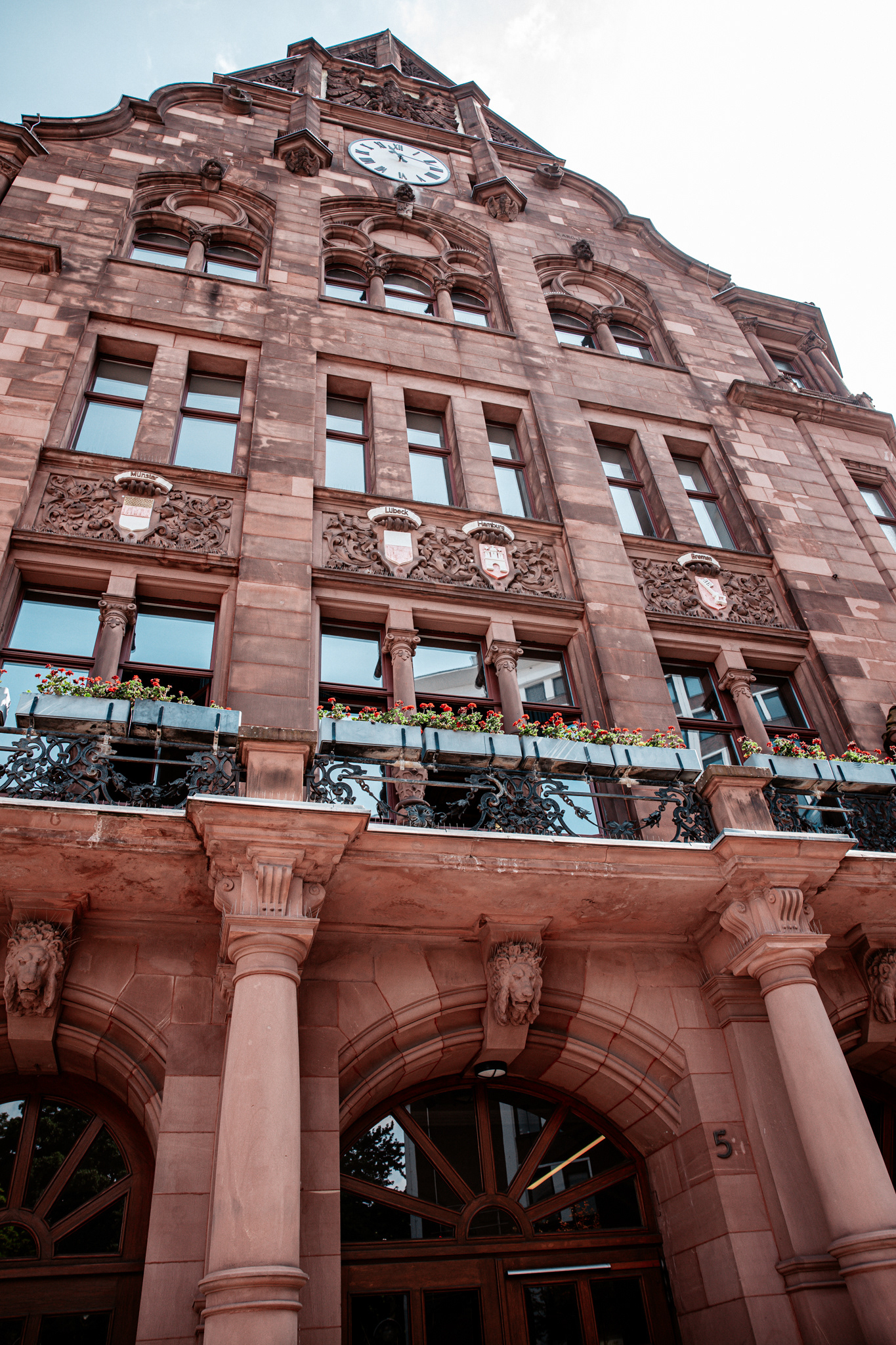Frontansicht des historischen Rathauses und Standesamts in Dortmund. Die beeindruckende Sandsteinfassade mit kunstvollen Verzierungen, Balkonen mit Blumendekoration und einer großen Turmuhr prägt das architektonische Erscheinungsbild des Gebäudes.