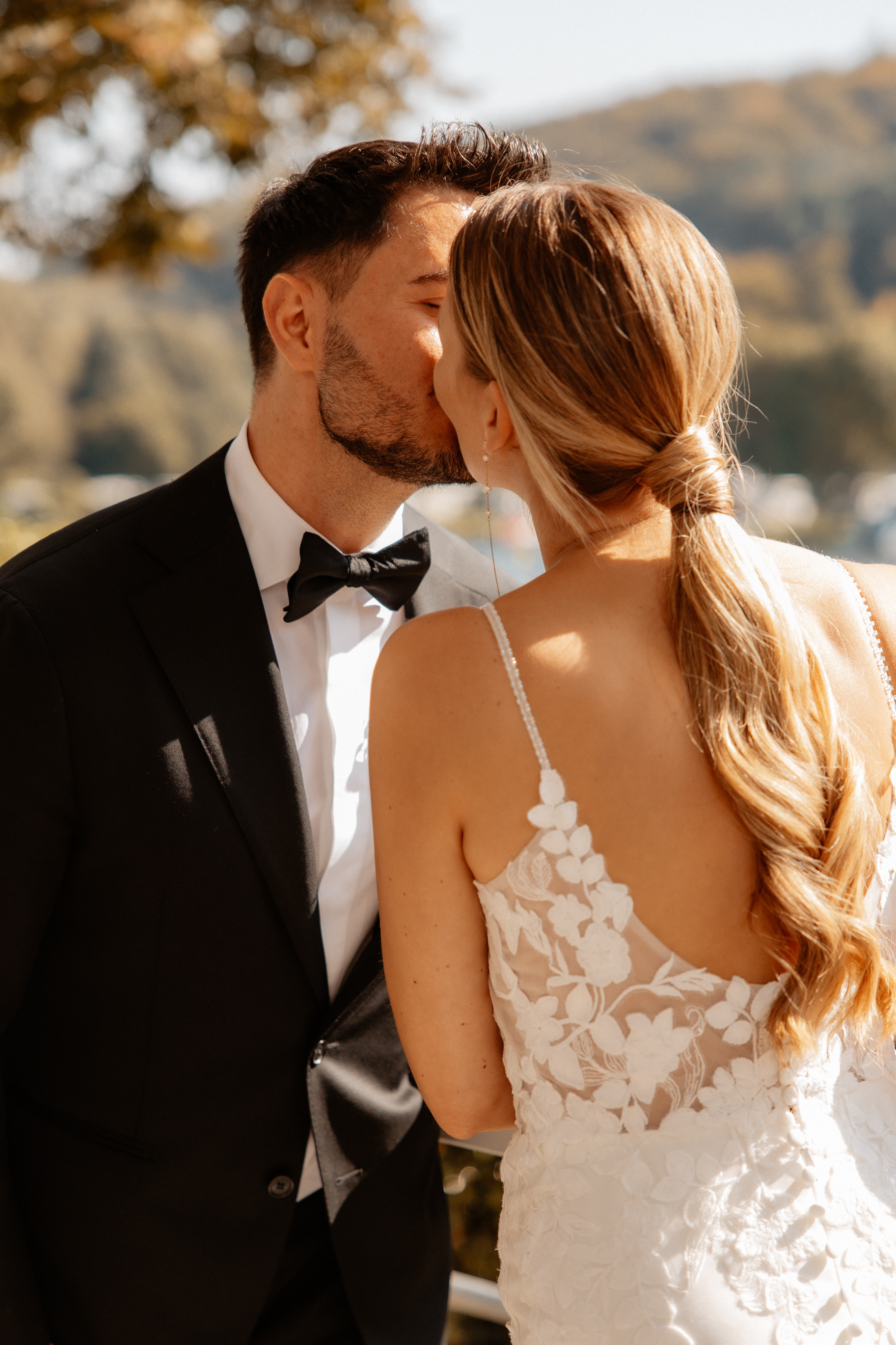 Das glückliche Brautpaar steht im Sonnenlicht, küsst sich und genießt einen ruhigen Moment für sich.
