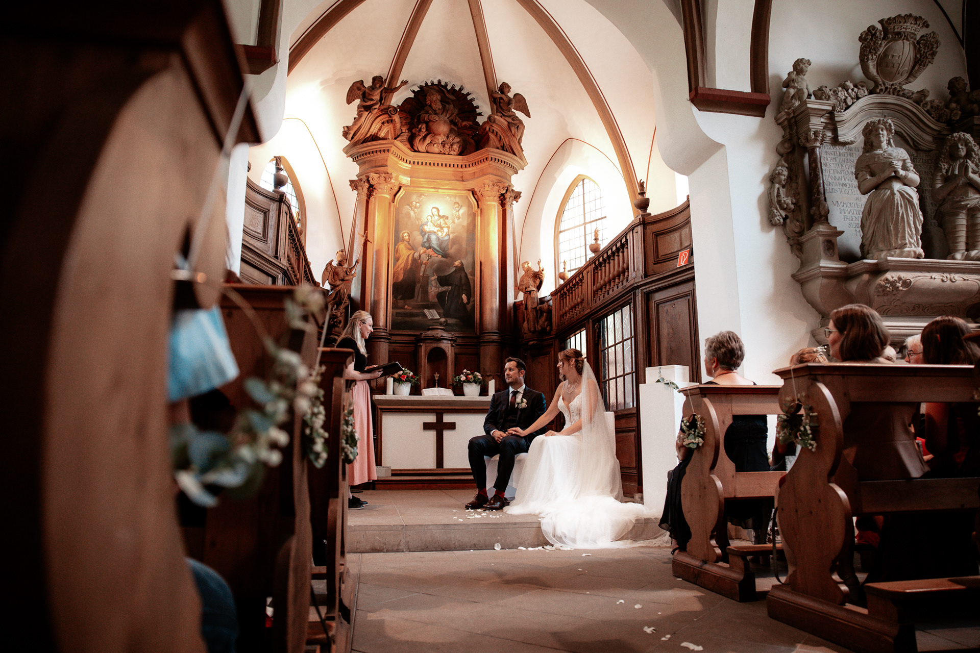 Trauung von Christina & Phillip – Das Brautpaar sitzt in der historischen Kirche von Schloss Herten während der feierlichen Hochzeitszeremonie. Emotionale Hochzeitsbilder mit authentischen Momenten.