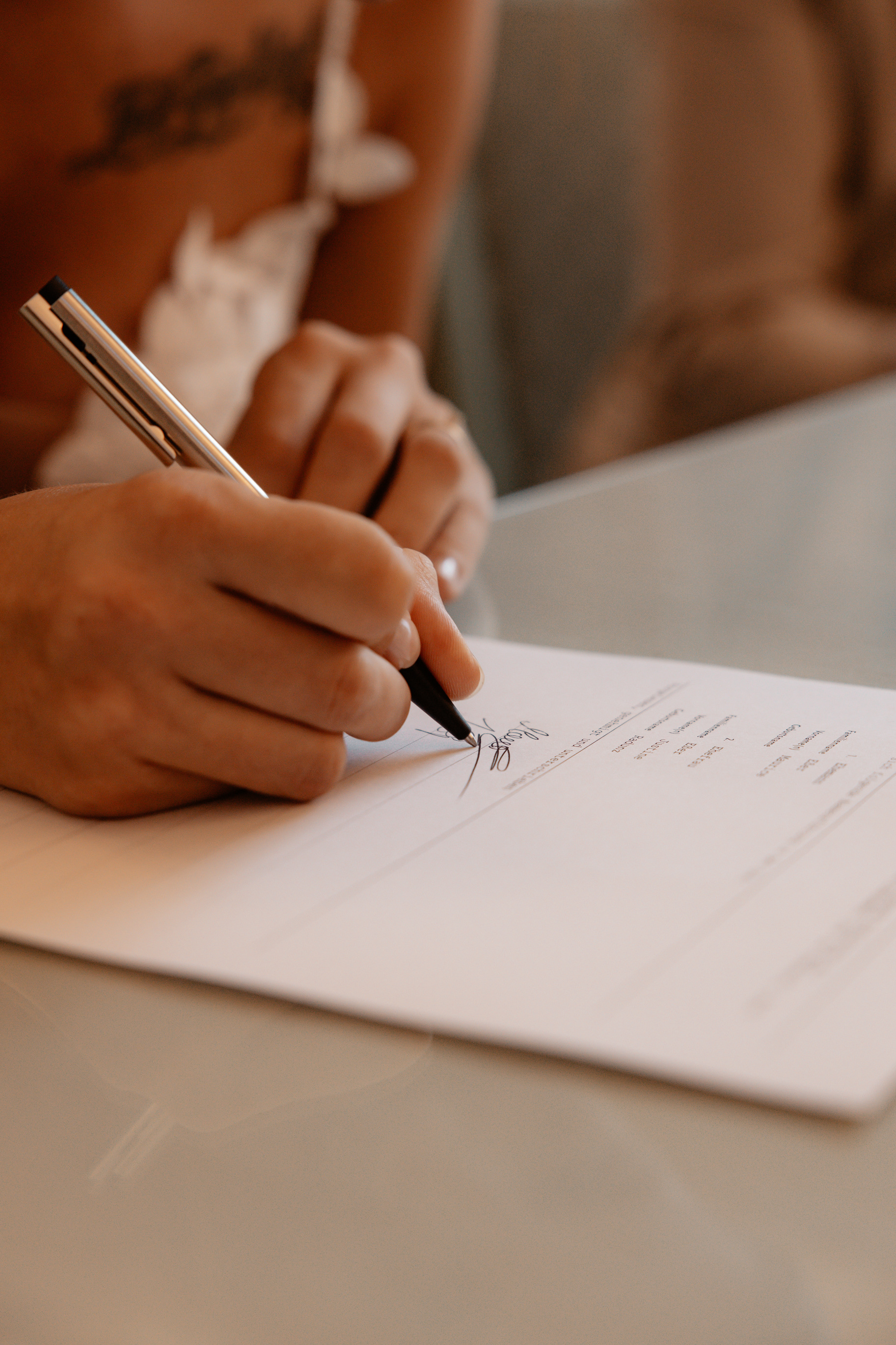 Nahaufnahme der Braut Justine, wie sie ihre Unterschrift auf die Heiratsurkunde setzt – ein bedeutungsvoller Moment der Eheschließung.