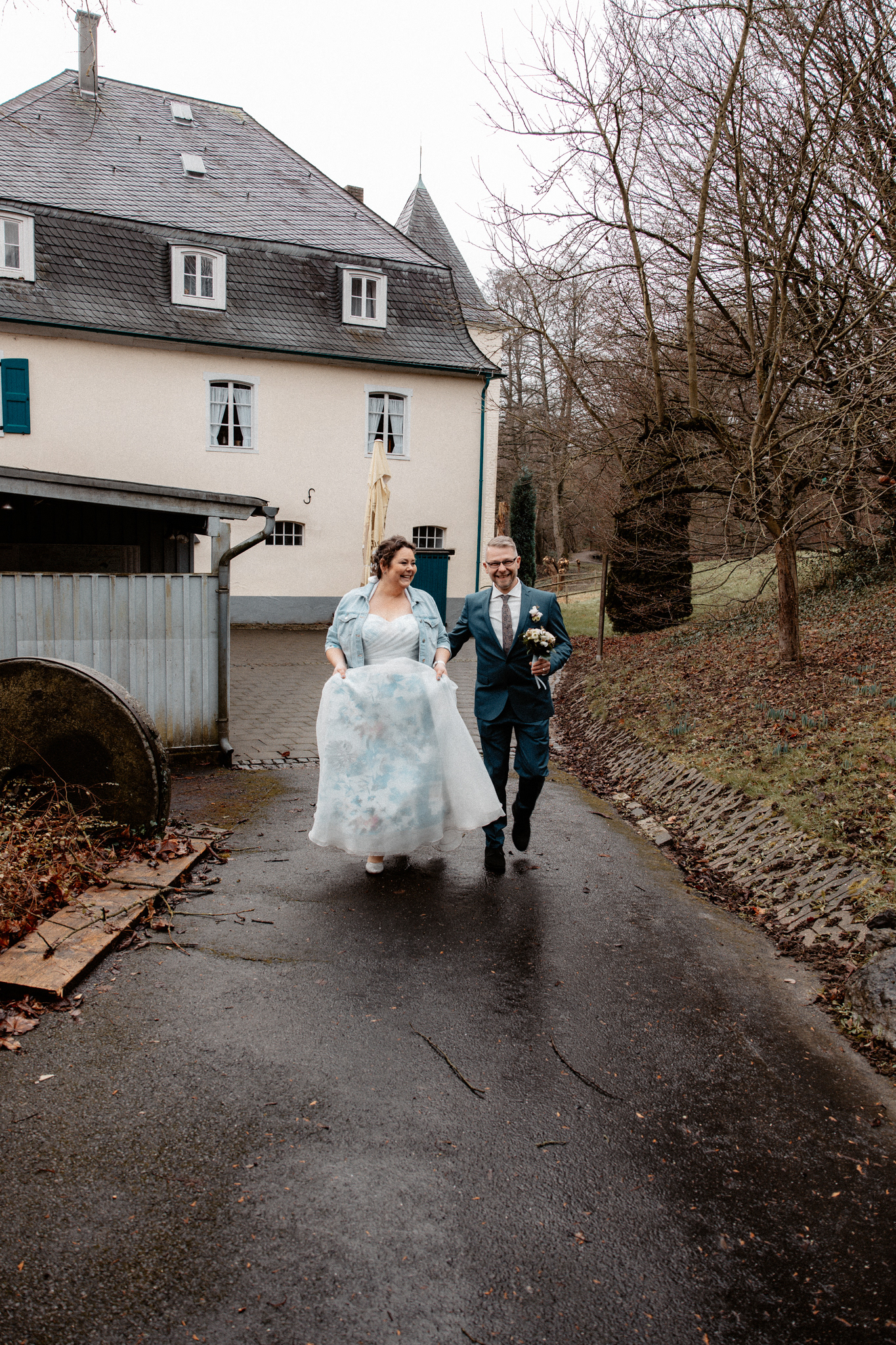 Claudia und Sven spazieren Hand in Hand durch das Gelände der Goldberger Mühle, während sie sich glücklich ansehen.