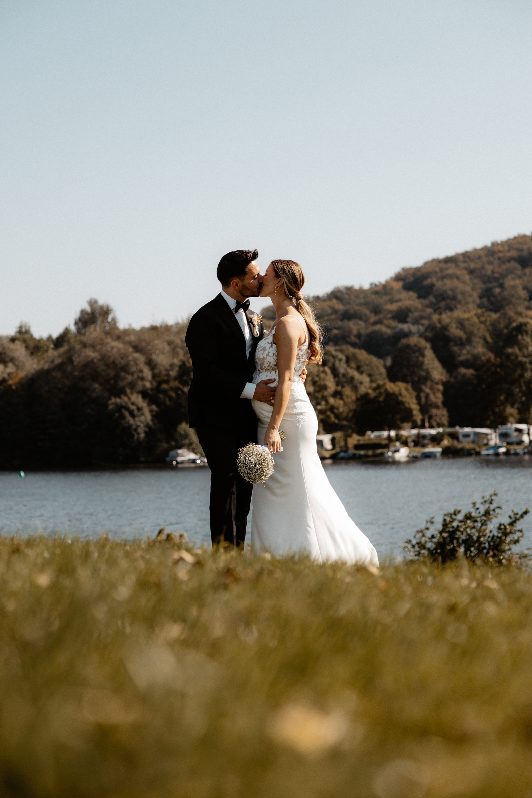 Der Hochzeitskuss am Seeufer – das Brautpaar teilt einen romantischen Moment inmitten der Natur.