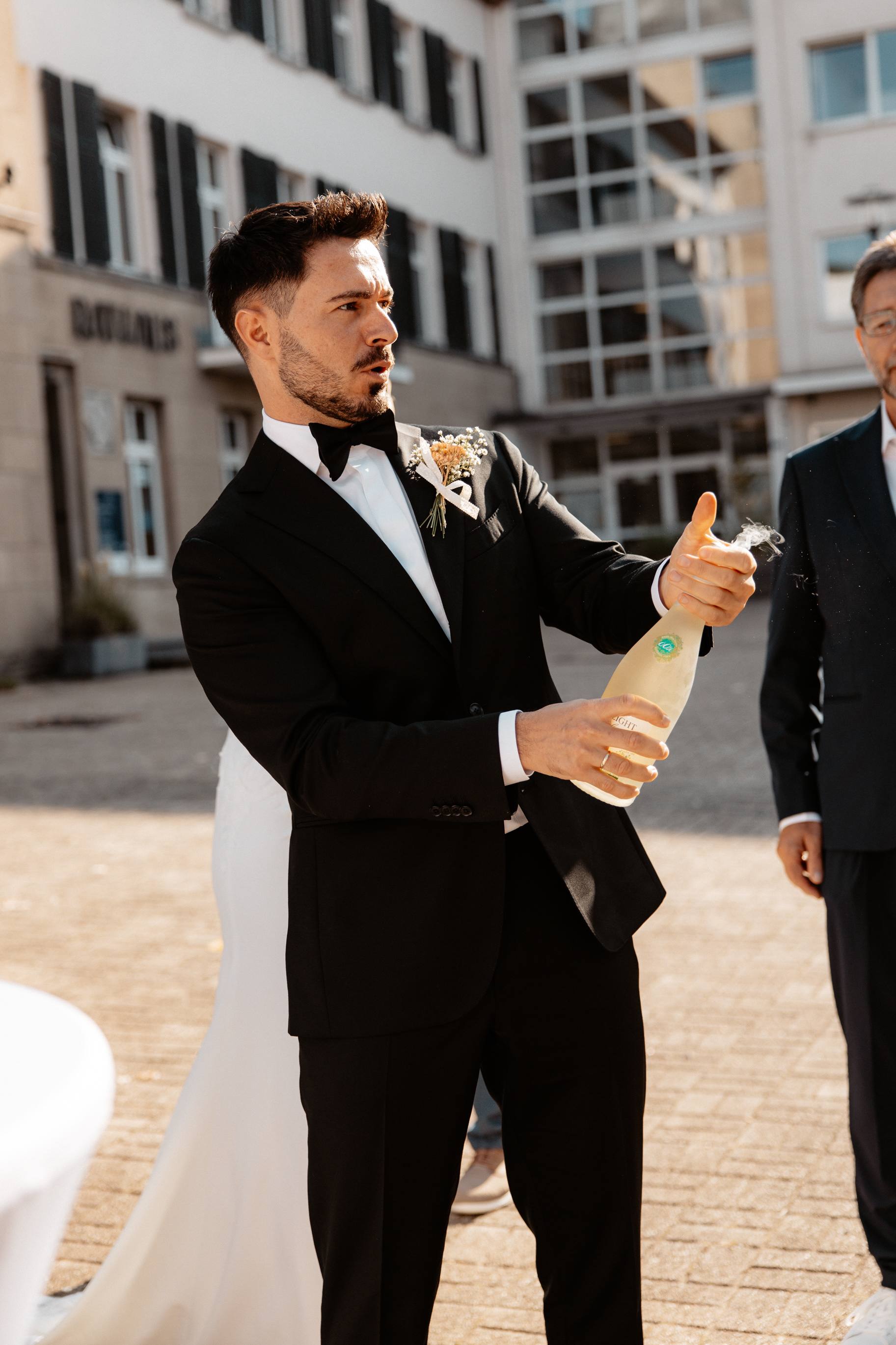 Bräutigam Maurice öffnet eine Flasche Sekt vor dem Rathaus in Essen-Kettwig, um auf die Hochzeit anzustoßen.