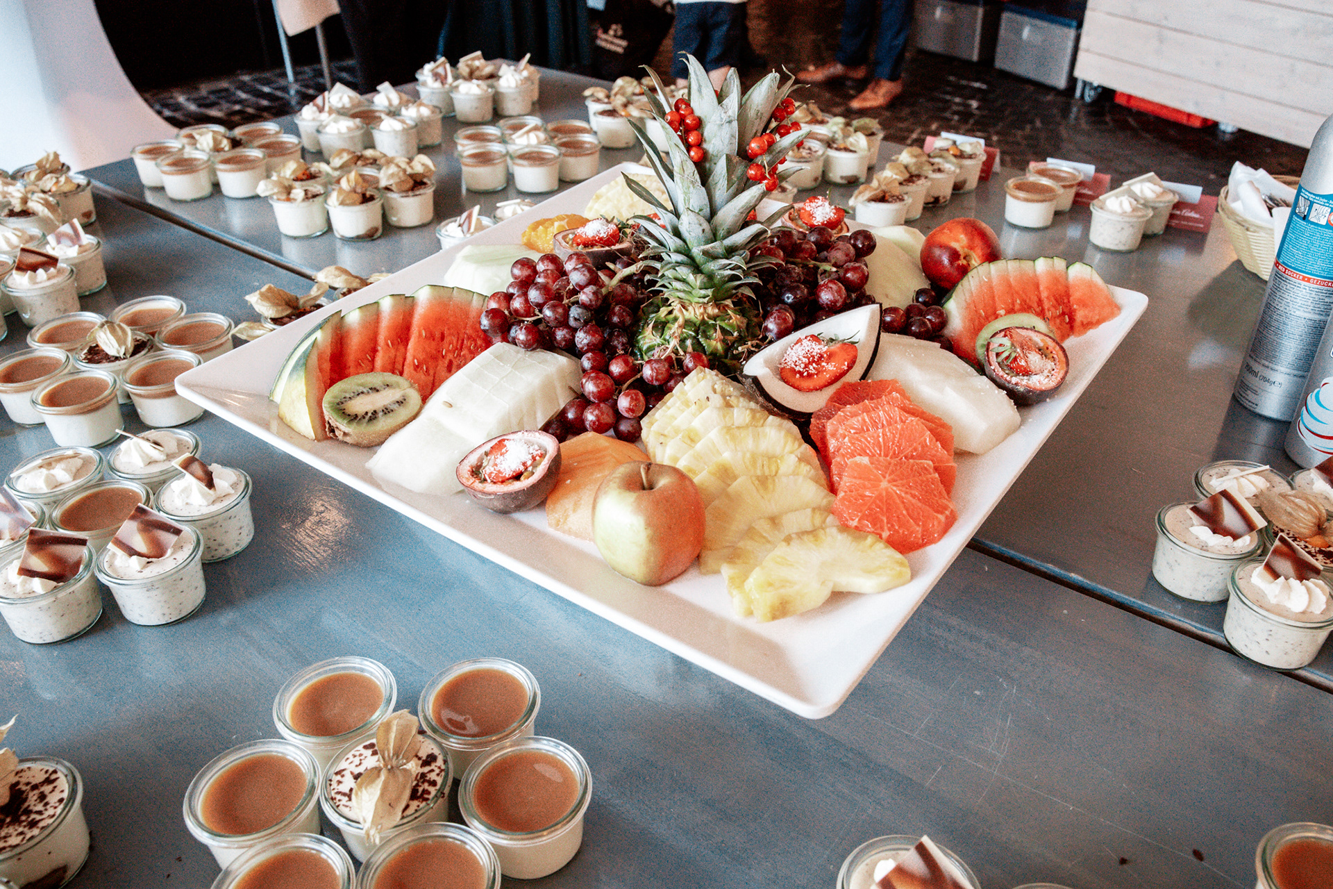 Farbenfrohes Hochzeitsbuffet mit frischem Obst und süßen Desserts. Die Hochzeit von Denise und Michael in Dortmund bietet eine große Auswahl an kulinarischen Highlights, liebevoll angerichtet mit frischen Früchten und Mini-Desserts.