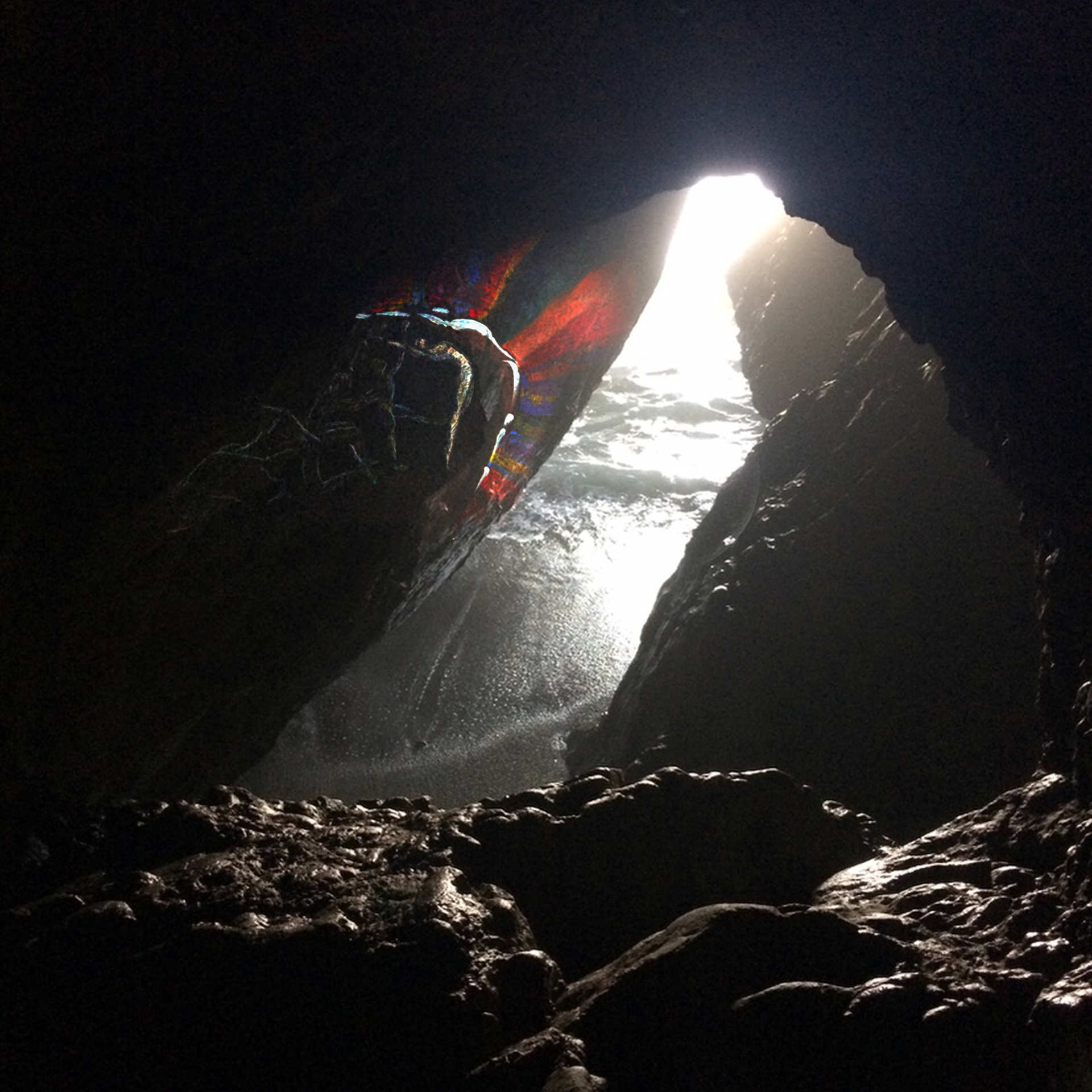 Album art for unfolding - a photo of a cave with a figure emerging