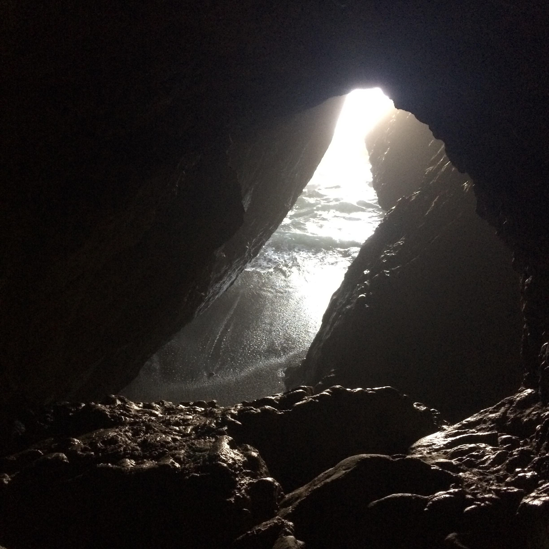 A photo of a cave, from the inside looking out toward the sun