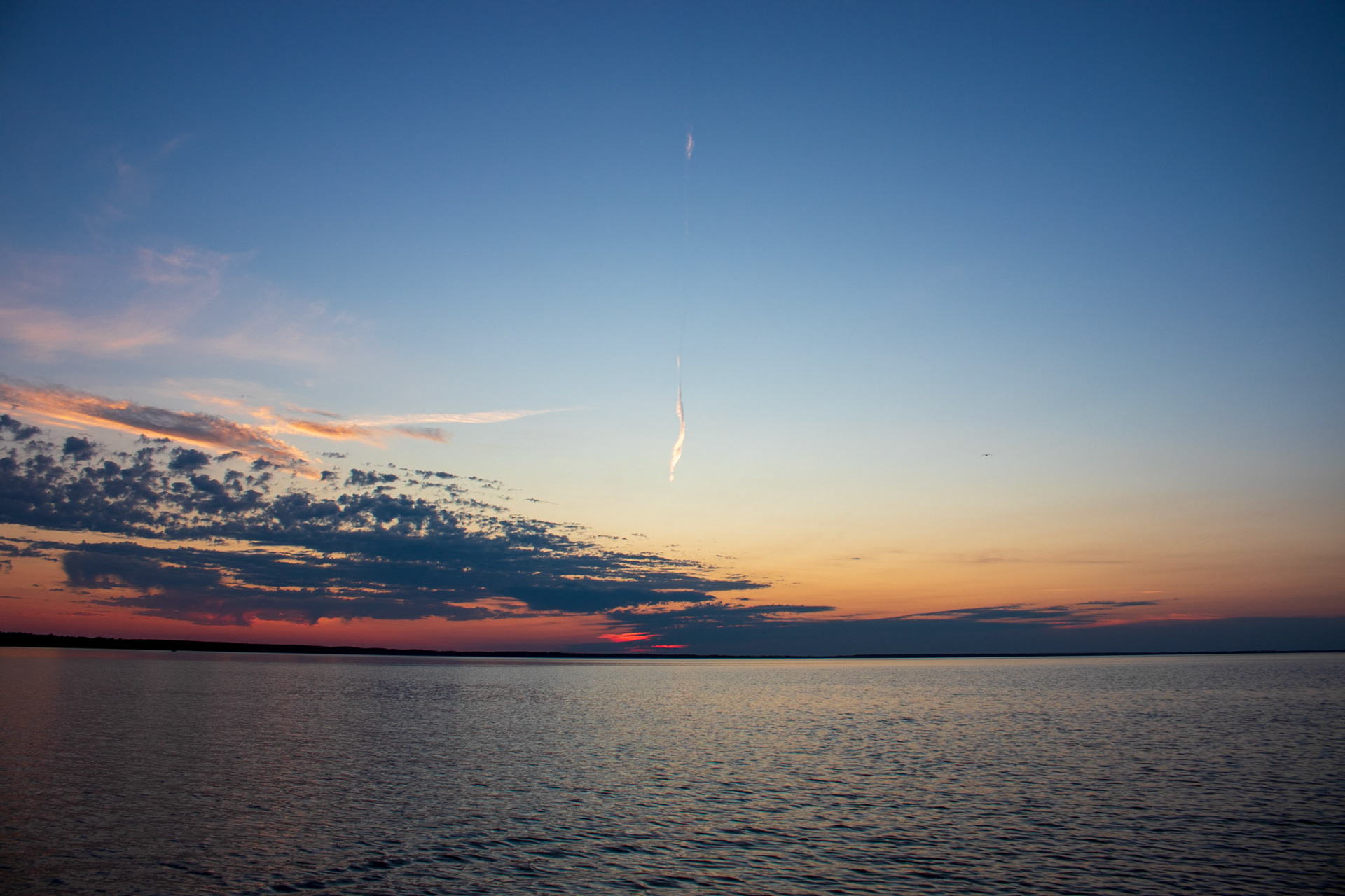 Sunset, clouds, and an airplane contrail over Lake Winnibigoshish