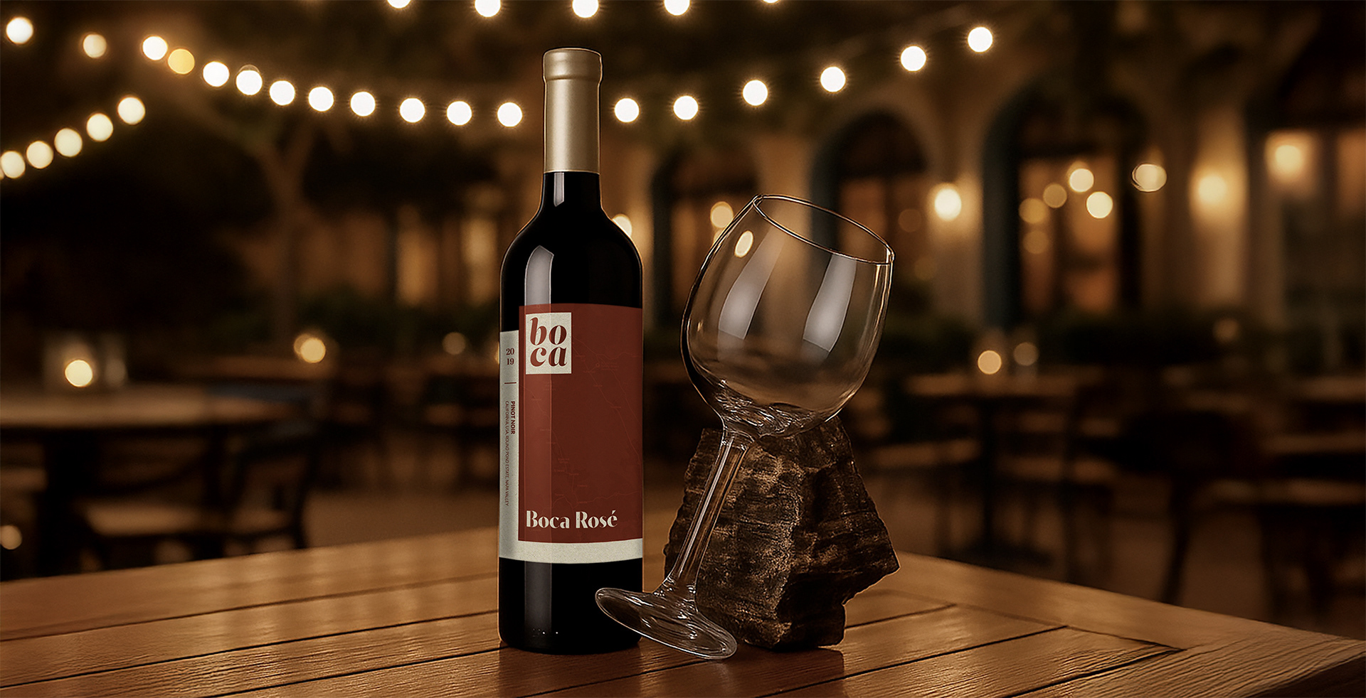 Boca Rosé wine bottle with label next to an empty glass in a restaurant setting, designed by Jorda Thomas.