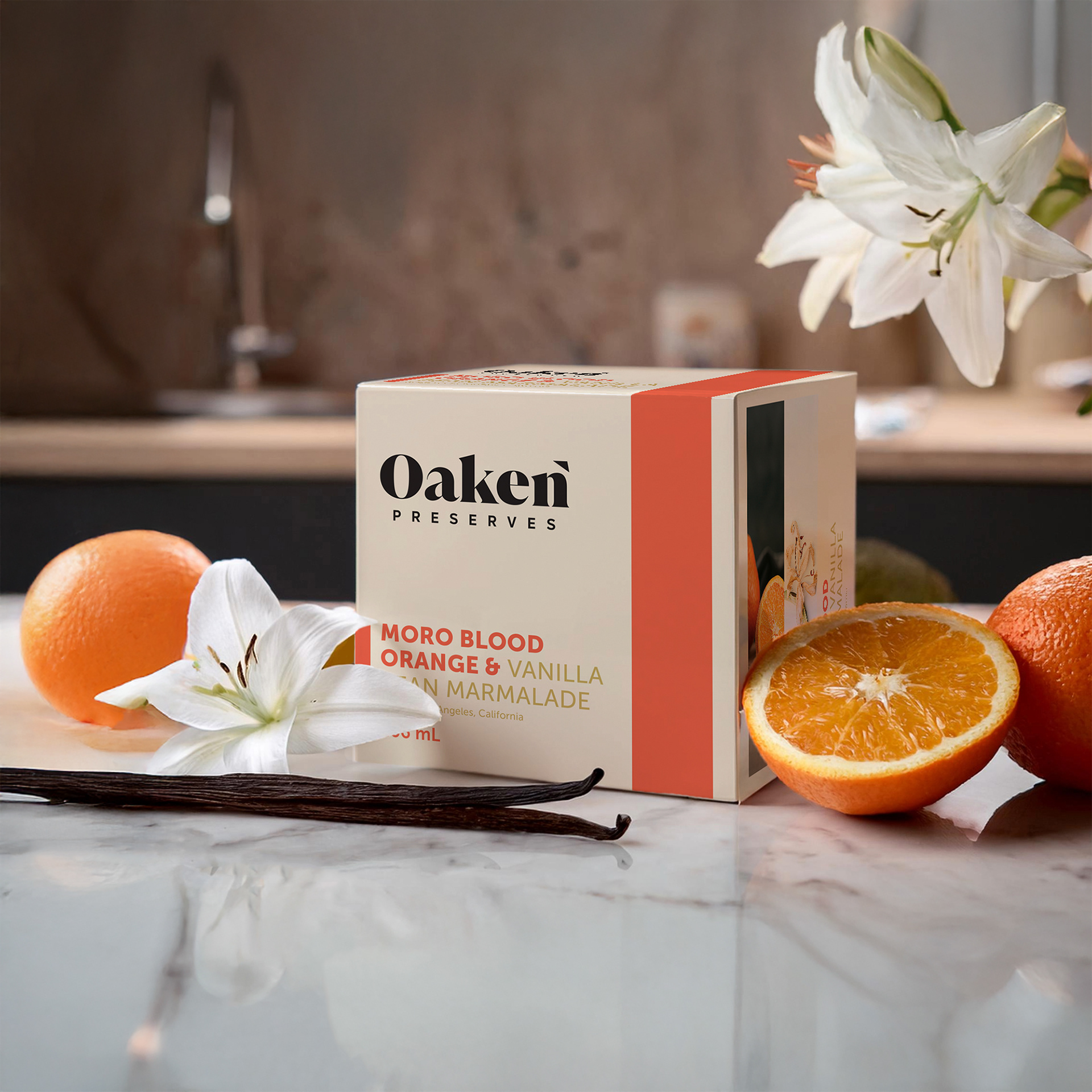 Oaken Preserves jam box on marble kitchen counter surrounded by oranges and vanilla flowers, designed by Jorda Thomas.