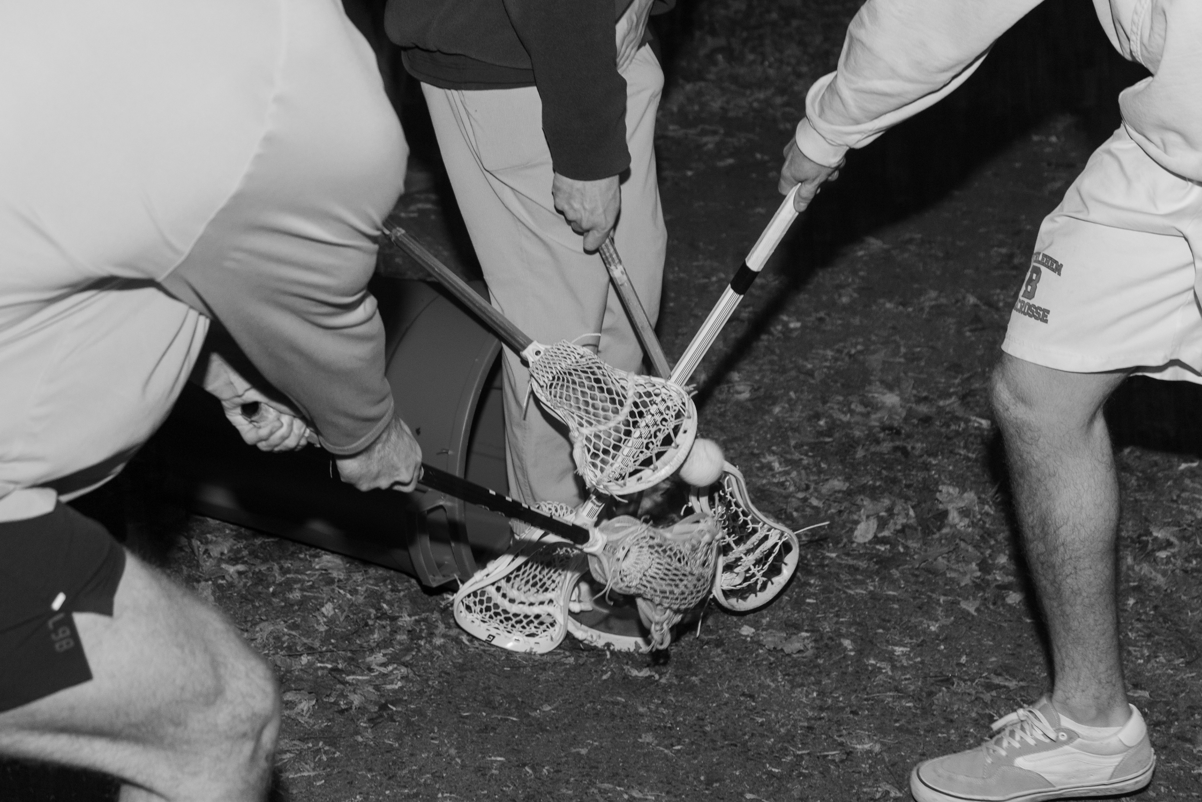Caelin Lewis, Jack Witherspoon, Jackson Birtwistle and Owen Hiltz practice lacrosse in their driveway. While all five are on the Syracuse University lacrosse team, the group of young athletes use an empty garbage can as a makeshift goal.