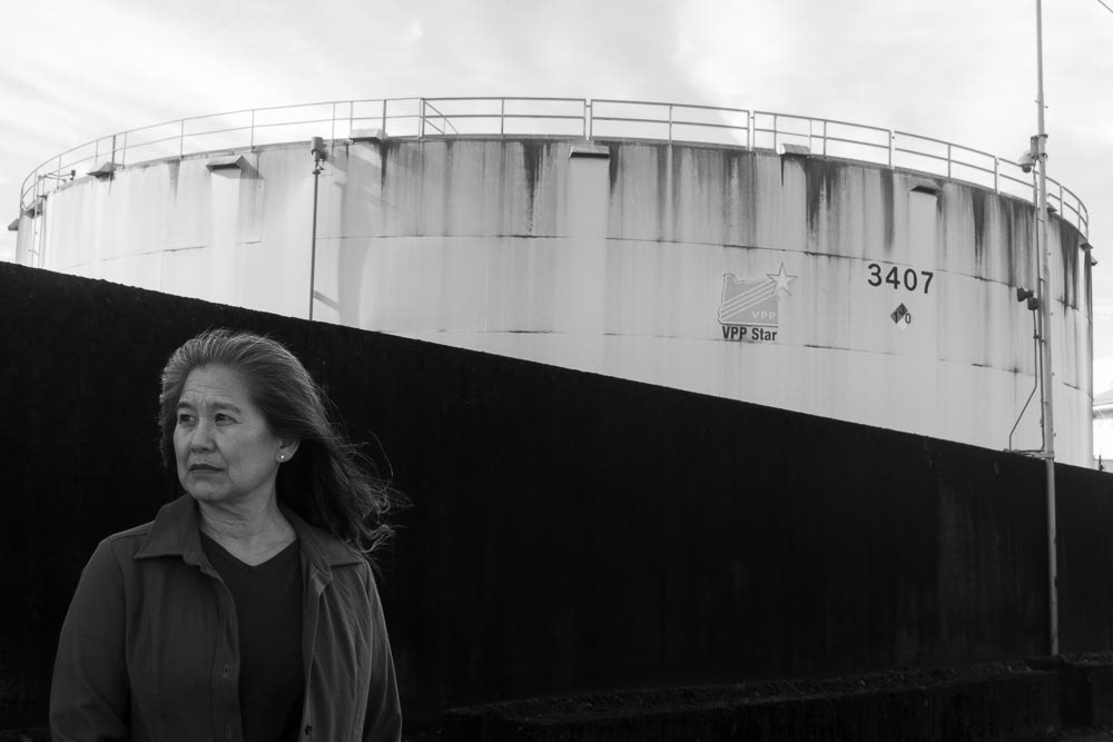 Yumei Wang stands in front of fuel tanks at the CEI hub. Wang was the first researcher to discover the soils sitting underneath the hub are extremely susceptible to liquefaction — a process in which normally solid land loses its strength when shaking occurs. She is the leading expert in this field and has published further reports and continued to advocate for action to make the hub seismically secure. 