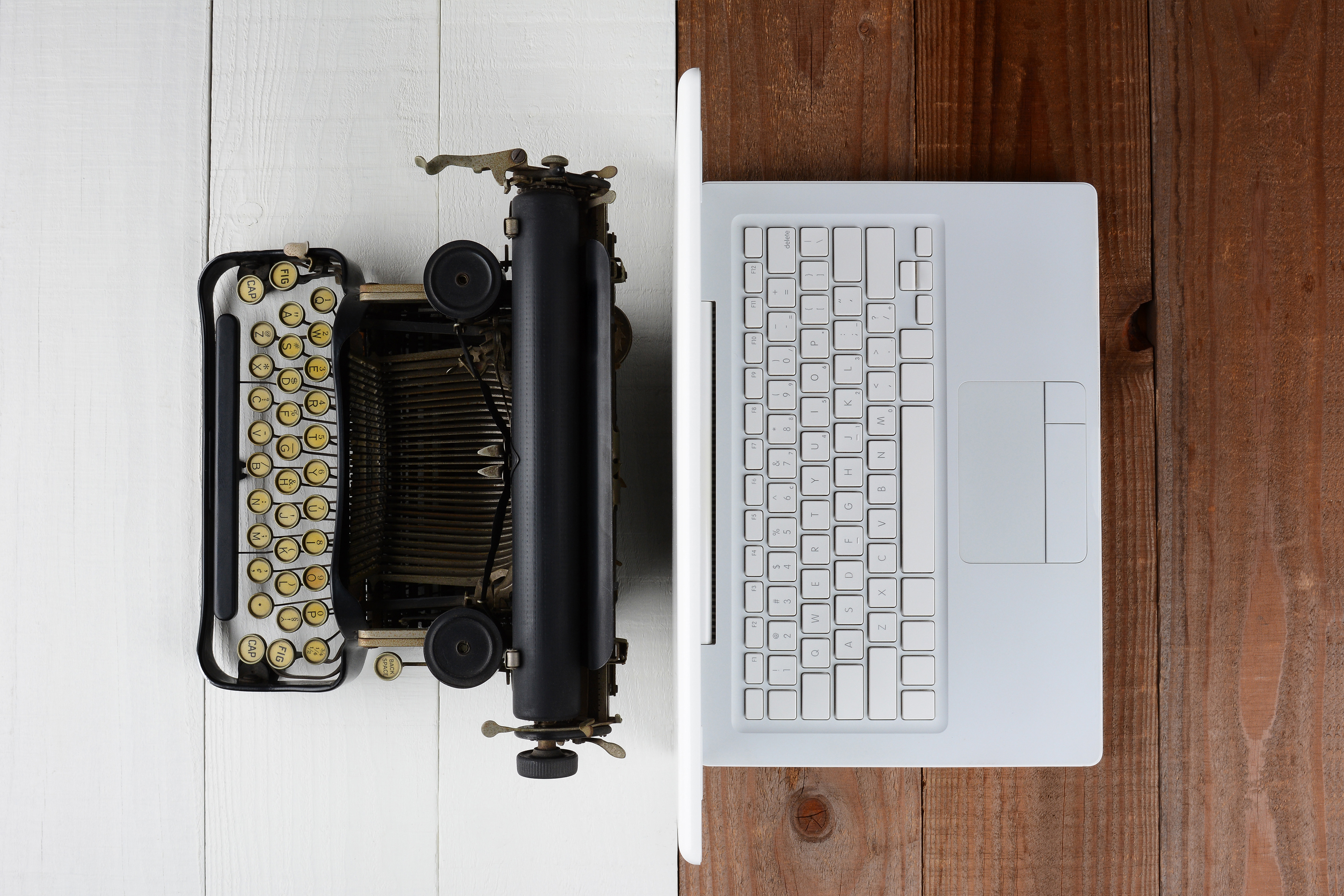 An image showing a contrast between an old typewriter and a modern laptop, symbolizing Pan_Inc’s commitment to enhancing traditional instruments with contemporary precision and care.