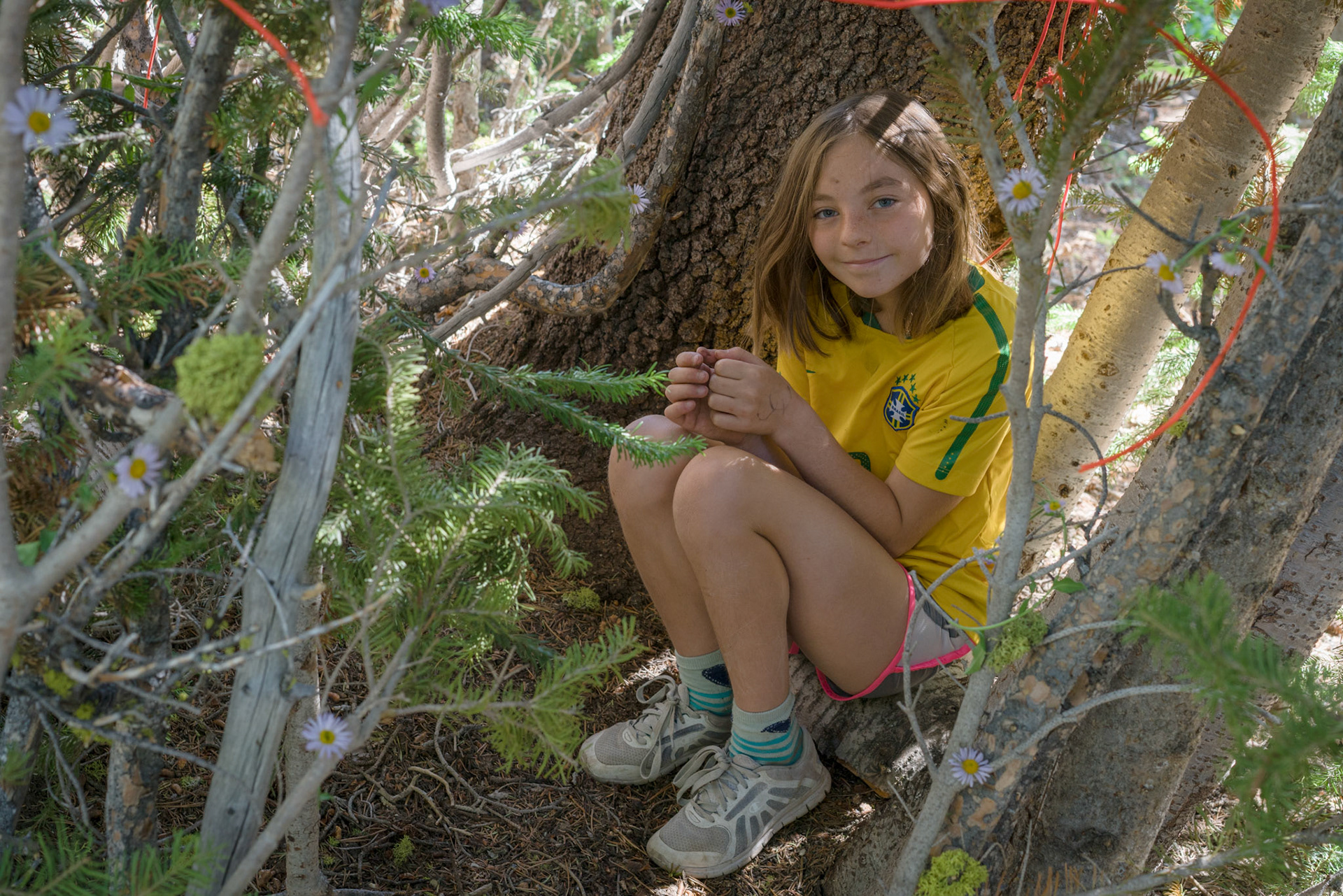 Brenna decorates her fort’s walls with last night’s bouquet and red twine she found along the shore.