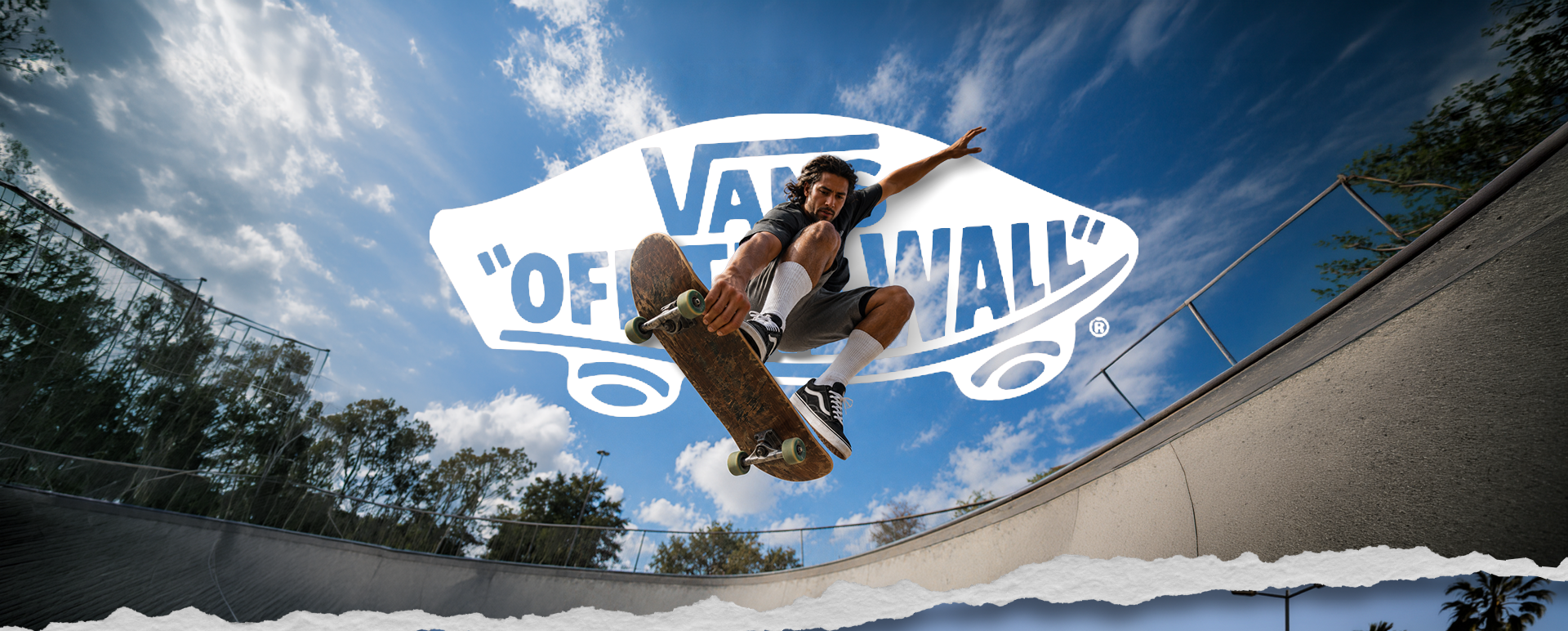 Skater en pleno salto sobre una rampa, con el logotipo Vans Off The Wall y un cielo azul de fondo.