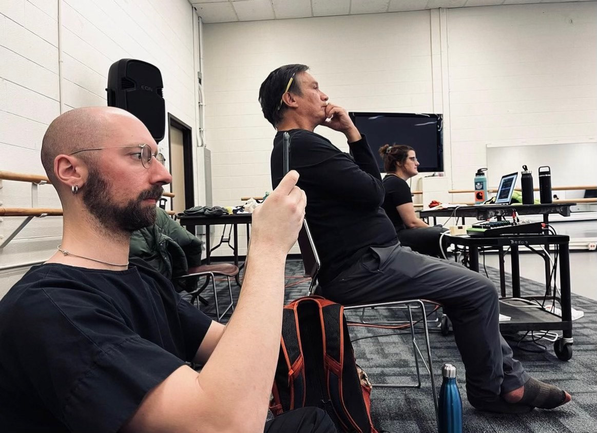 Three people watching a rehearsal