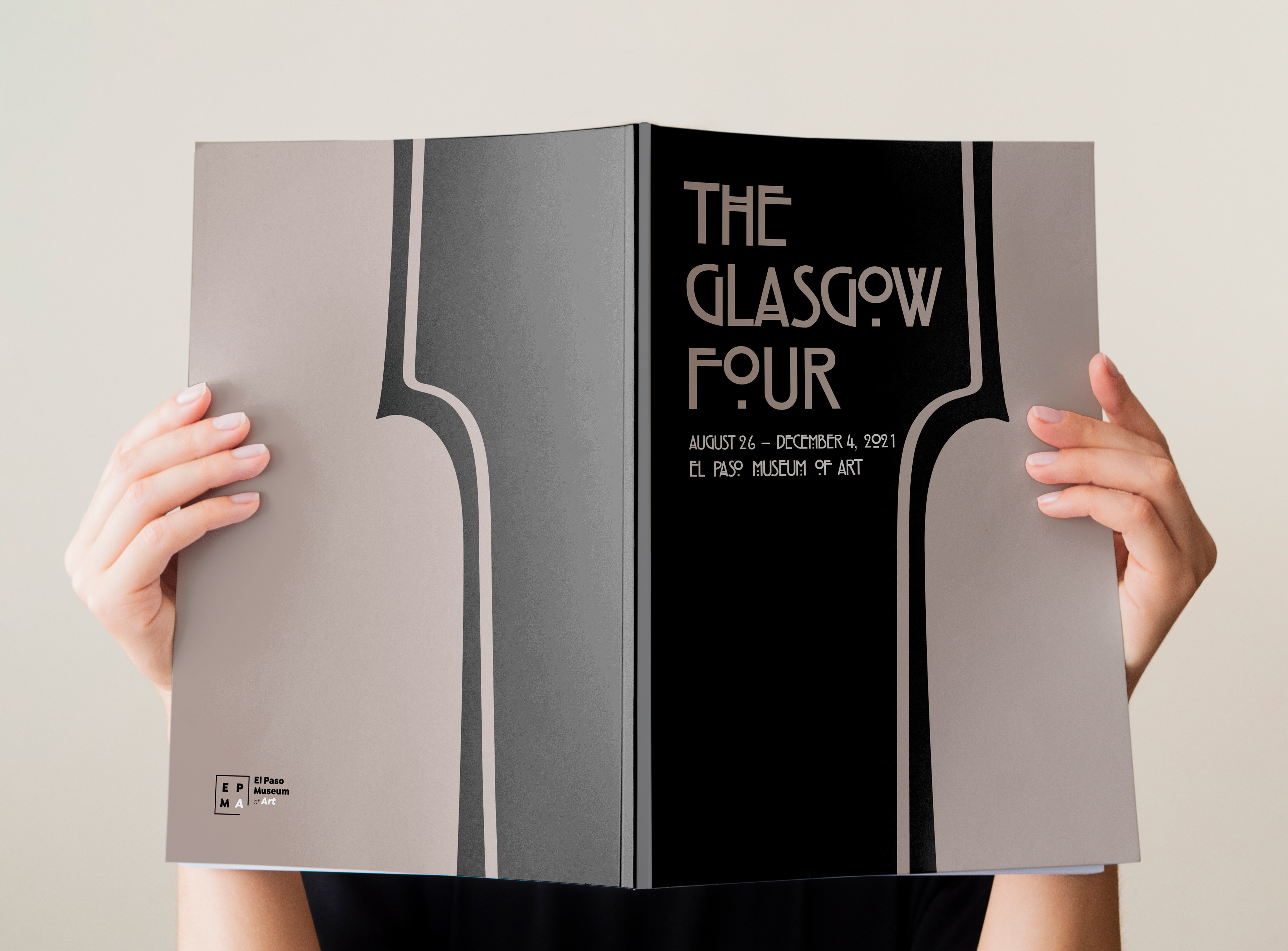 Person holding up the museum catalog with covers facing forward. The front cover reads: The Glasgow Four, August 26 to December 4th 2021. El Paso Museum of Art.