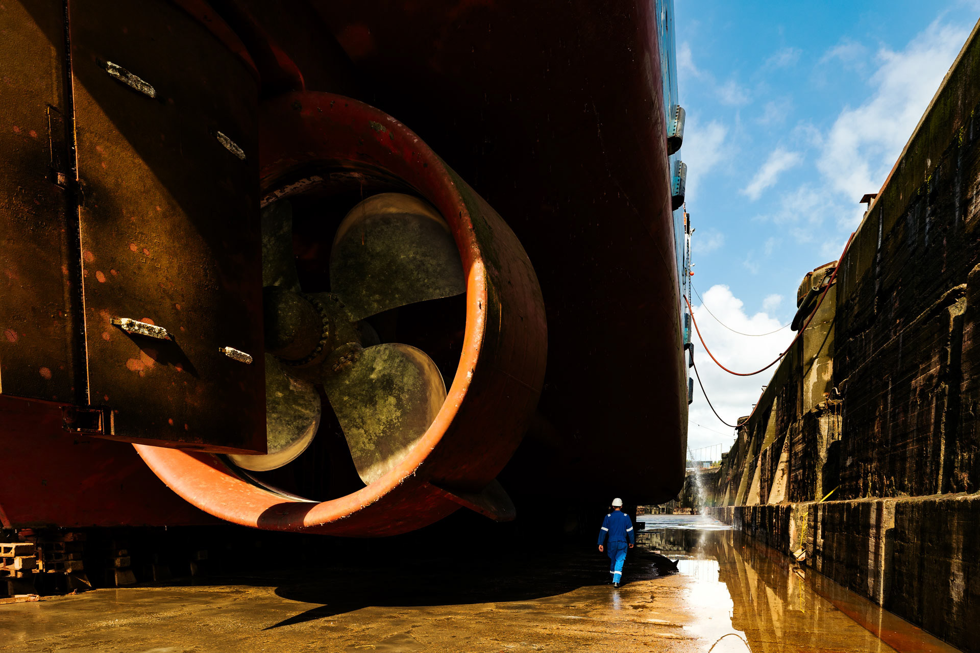 Man loopt naast schip in droogdok bij Damen Shipyard