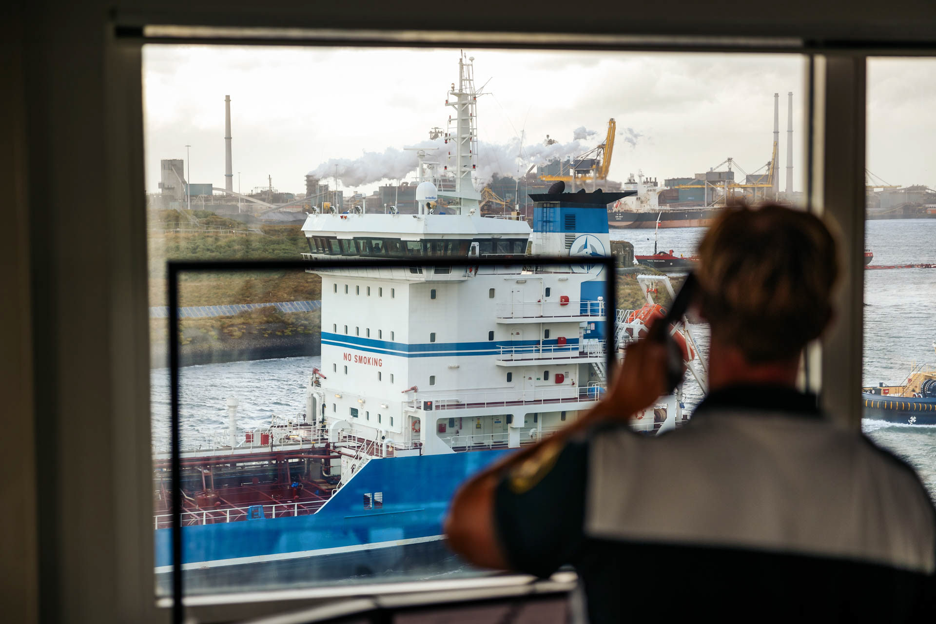 Industriele fotografie - Havenbeampte telefonerend terwijl vrachtschip langs vaart
