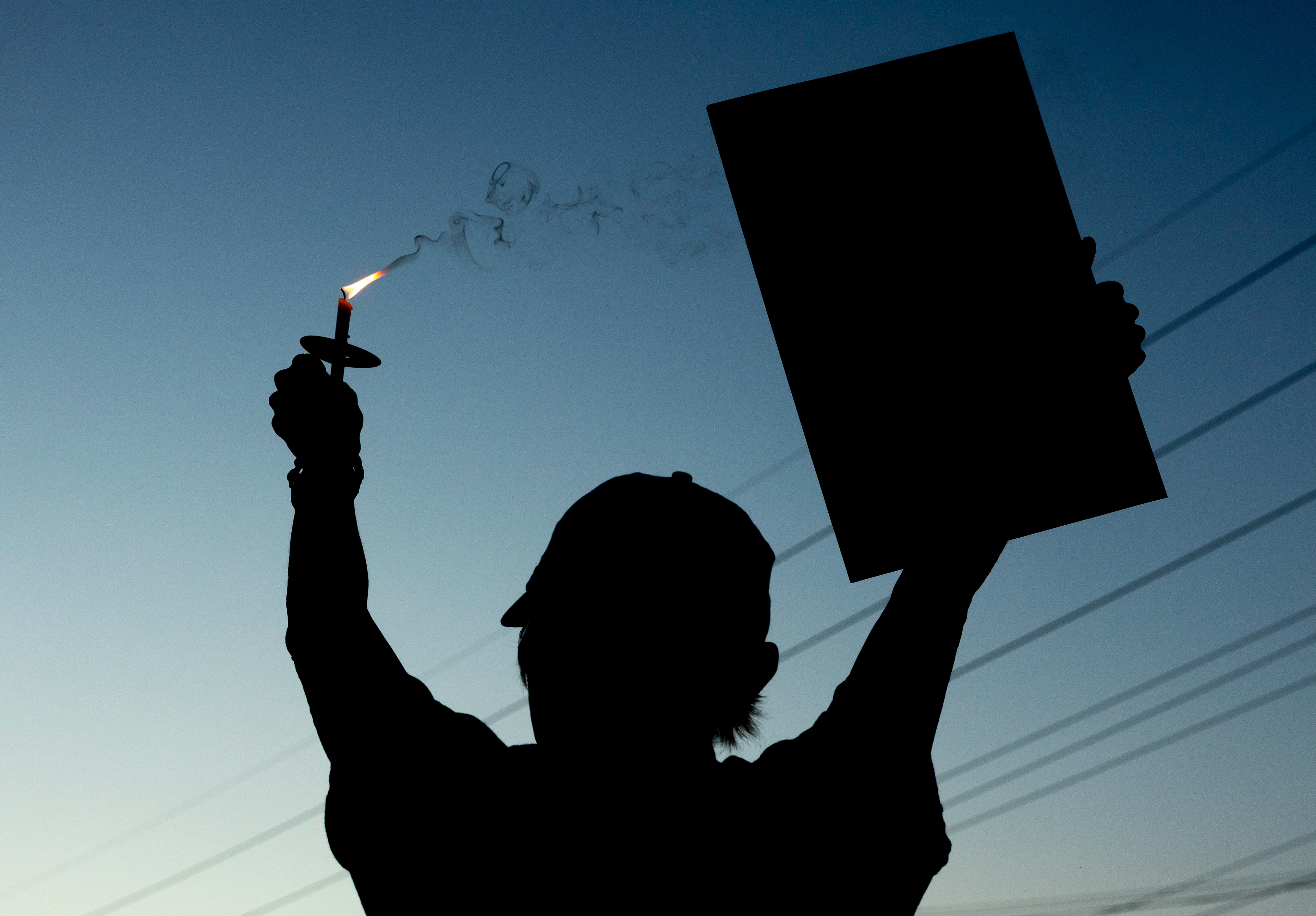 Sharon Campshure proudly waves her candle and sign to passing cars at the ICE victim candlelight vigil on Monday, Sept. 15, 2025 outside of ICE Headquarters in Bowling Green. 