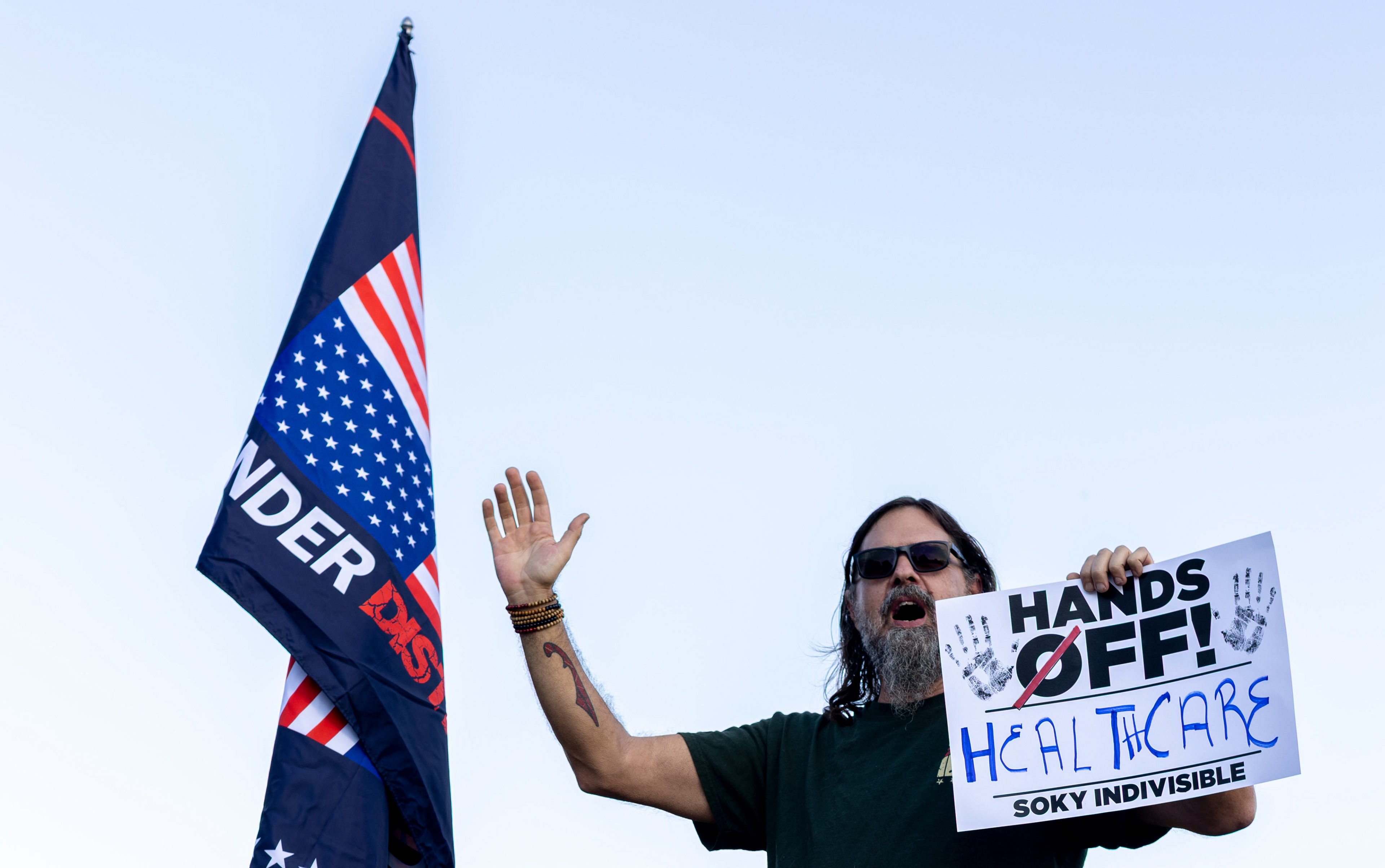 Former U.S. Marine Joel Extine waves to passing cars at a protest held by SoKy Indivisible outside of U.S. Rep. Brett Guthrie’s office on Thursday, Oct. 2, 2025. Extine said in an interview, “Even as a 100% disabled veteran, I still can’t get proper care. Guthrie, even as a veteran himself, won’t help out.”