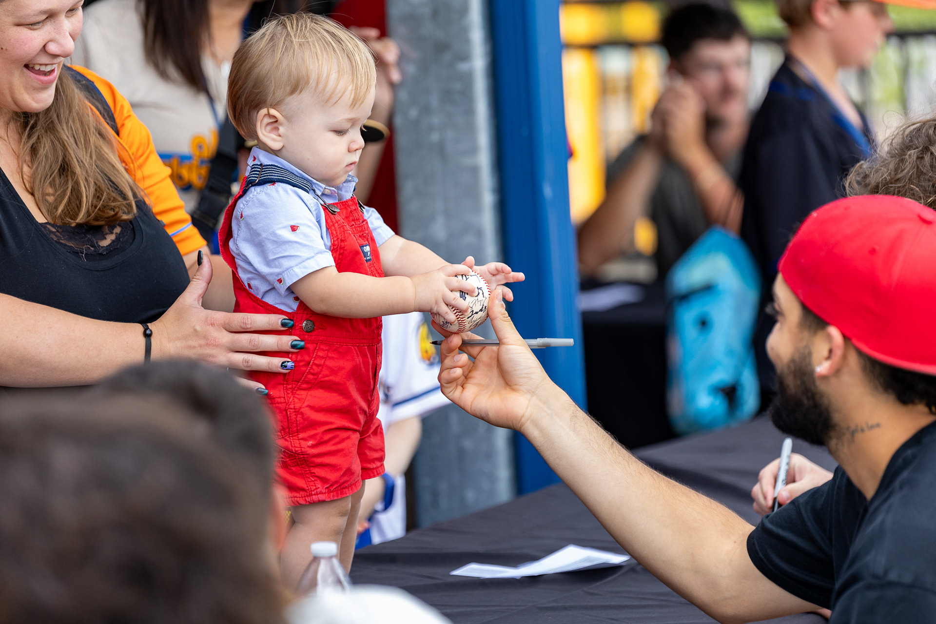 Alexfri Planez signs a little kid's ball after a walk-off win at Canal Park on August 11 2024.