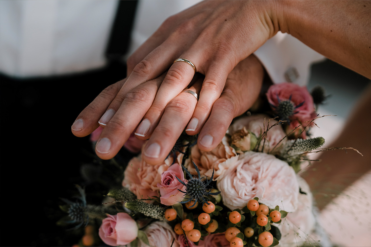 Close-up der Hände und Eheringe des Hochzeitspaares