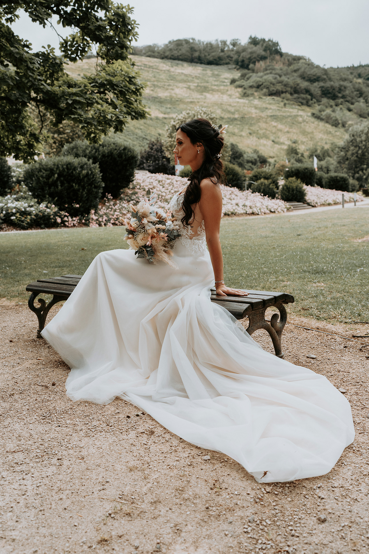 Braut alleine sitzend auf der Bank mit wunderschönem Brautkleid