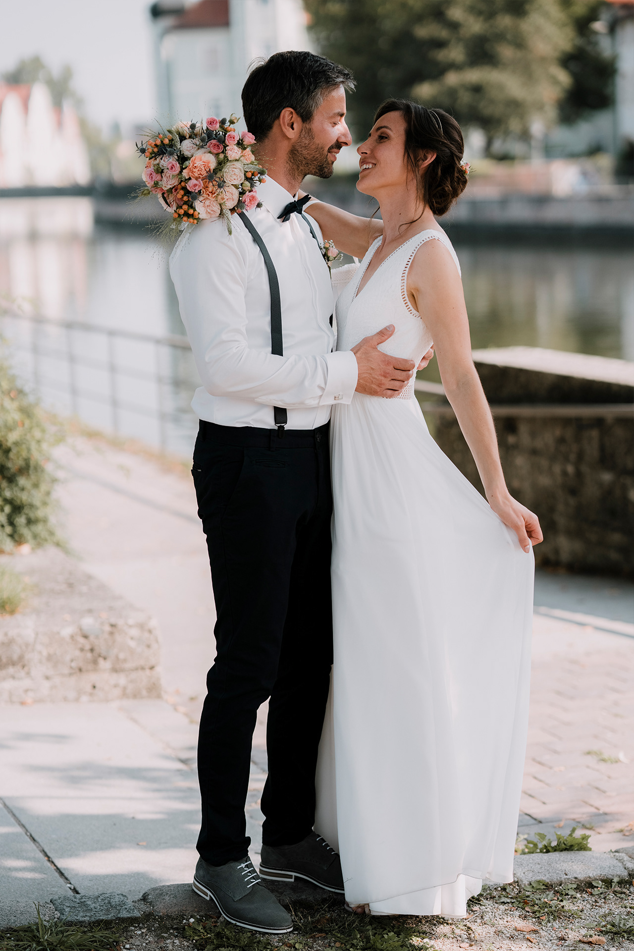 Braut greift ihr Brautkleid und blickt ihrem Ehemann tief in die Augen