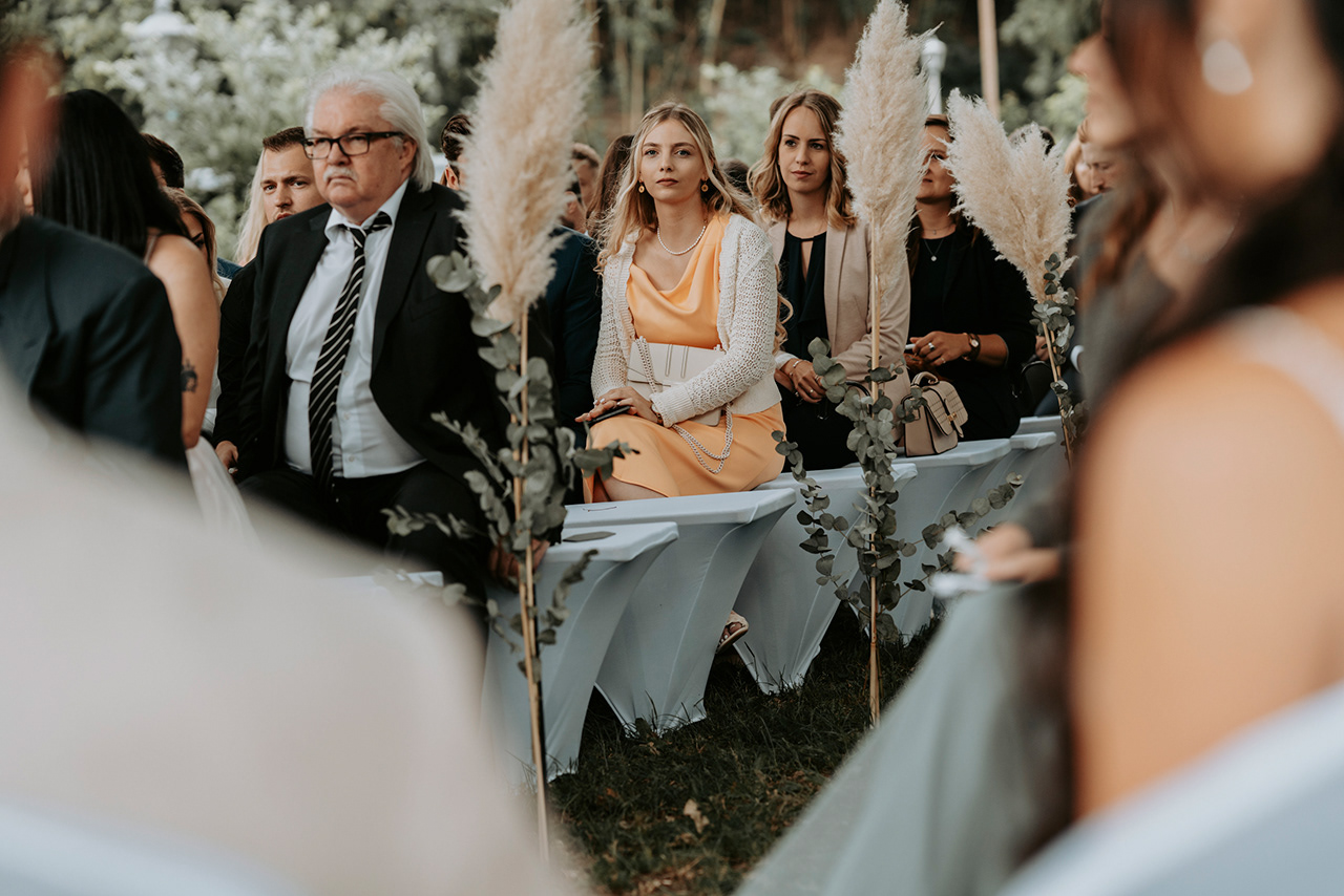 Hochzeitsgast in orangefarbenem Kleid bei Trauung im Freien