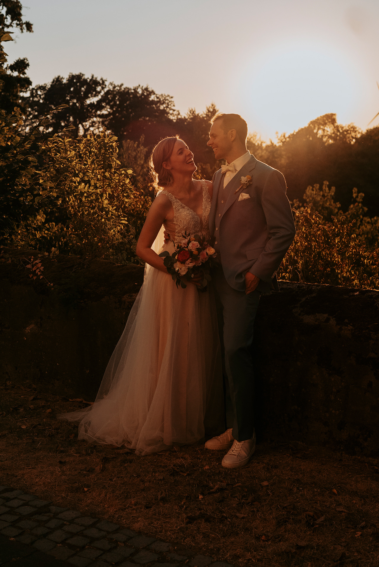 Hochzeitspaar lachend bei Sonnenuntergang