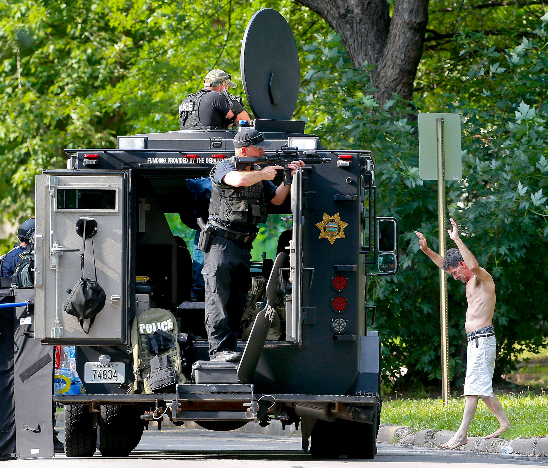 With guns drawn on him, the man suspected of shooting an innocent bystander while trying to shoot a woman at the nearby BP gas station Monday afternoon walks out of a house near Washburn Avenue and S.W. 13th Street that he barricaded himself in for nearly six hours .