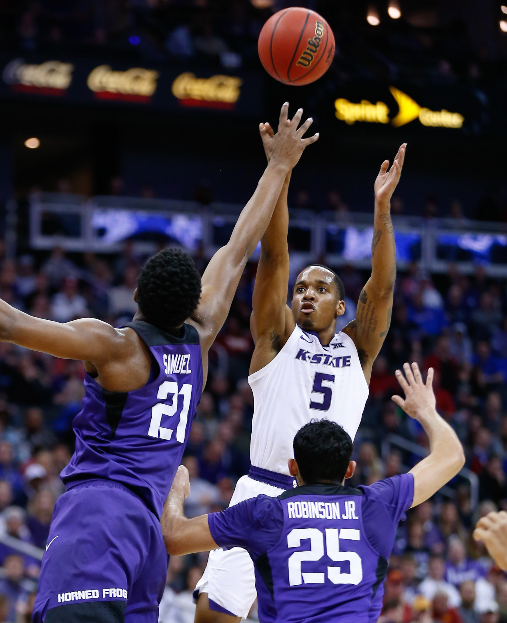 Kansas State guard Barry Brown, Jr. (5) scores a 3-pointer over TCU center Kevin Samuel (21) and guard Alex Robinson  (25) during the first half of an NCAA college basketball game in the Big 12 men's tournament Thursday, March 14, 2019, in Kansas City, Mo.