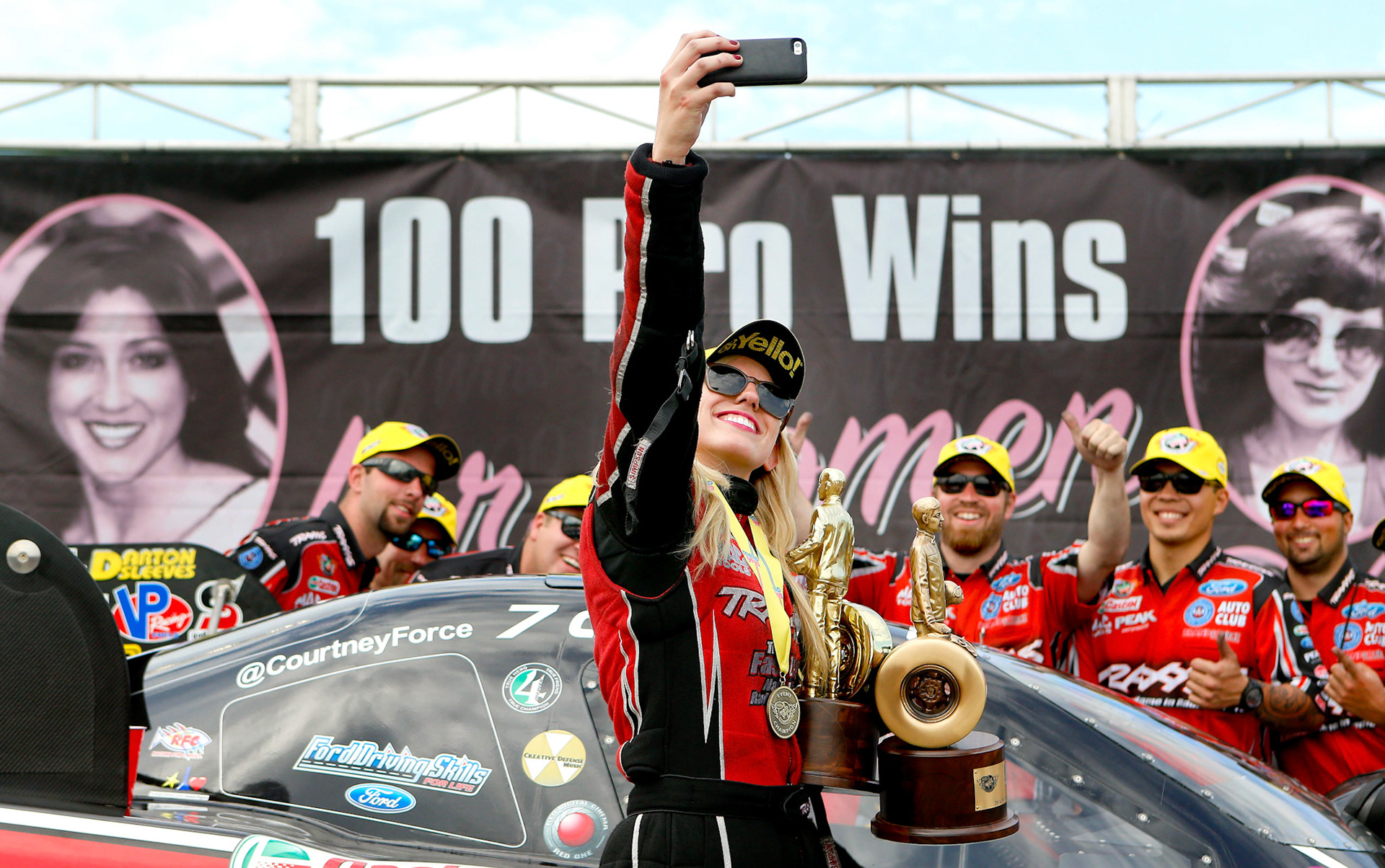 Funny Car driver Courtney Force takes a selfie with her team after winning the Kansas Nationals at Heartland Park marking the 100th professional win for women drivers in the NHRA on Sunday May 25, 2014.