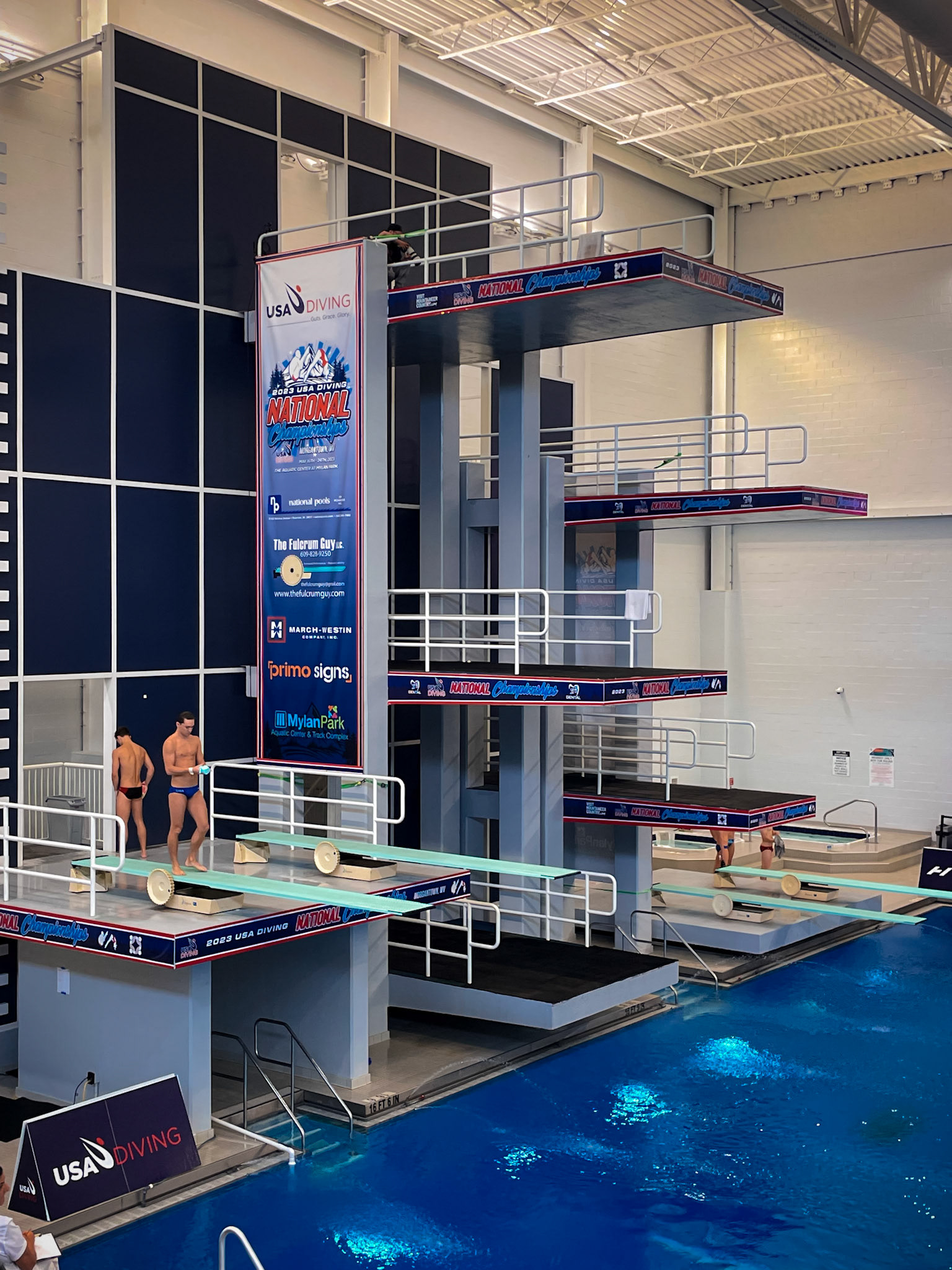 Nation Championships Banner and Platform Wraps on The Aquatic Center at Mylan Park's Diving Tower Side View with Divers on Spring Boards