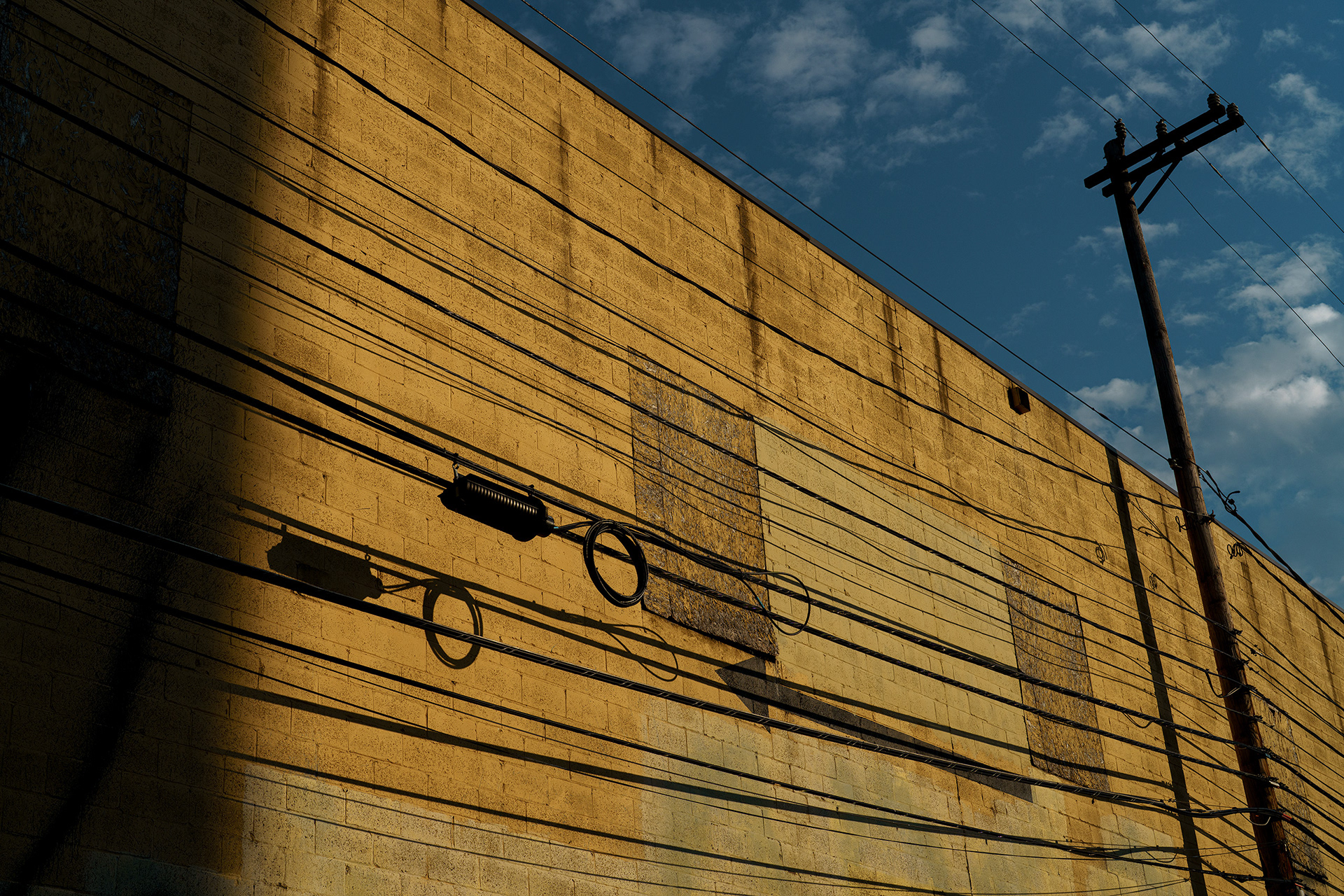 Yellow wall and deep blue shadow creating bold color contrast. Photograph by Ryan Bucchianeri highlighting modern composition.