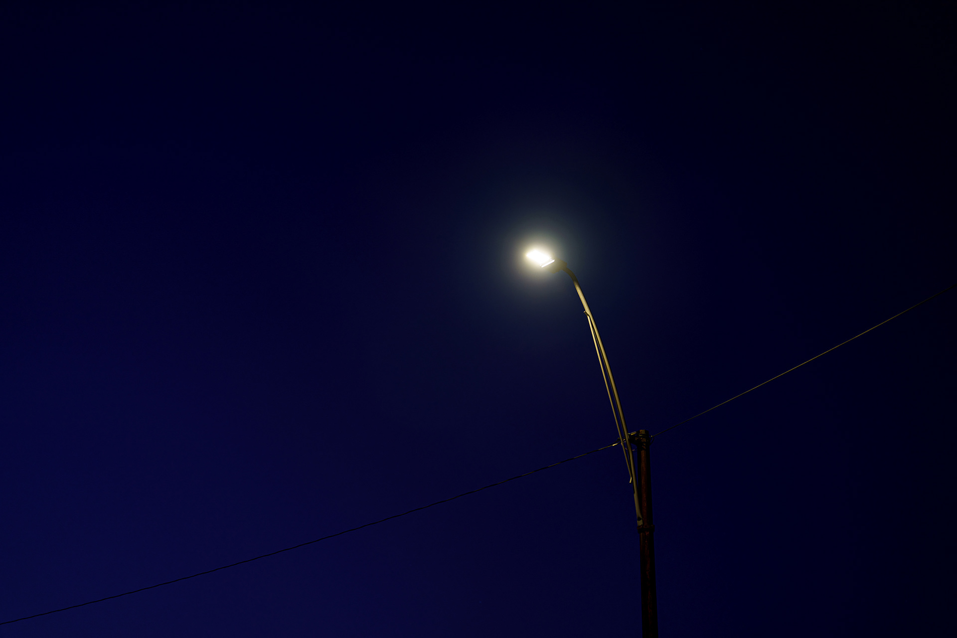 Solitary streetlight illuminated against deep blue night sky in photograph by Bucchianeri.