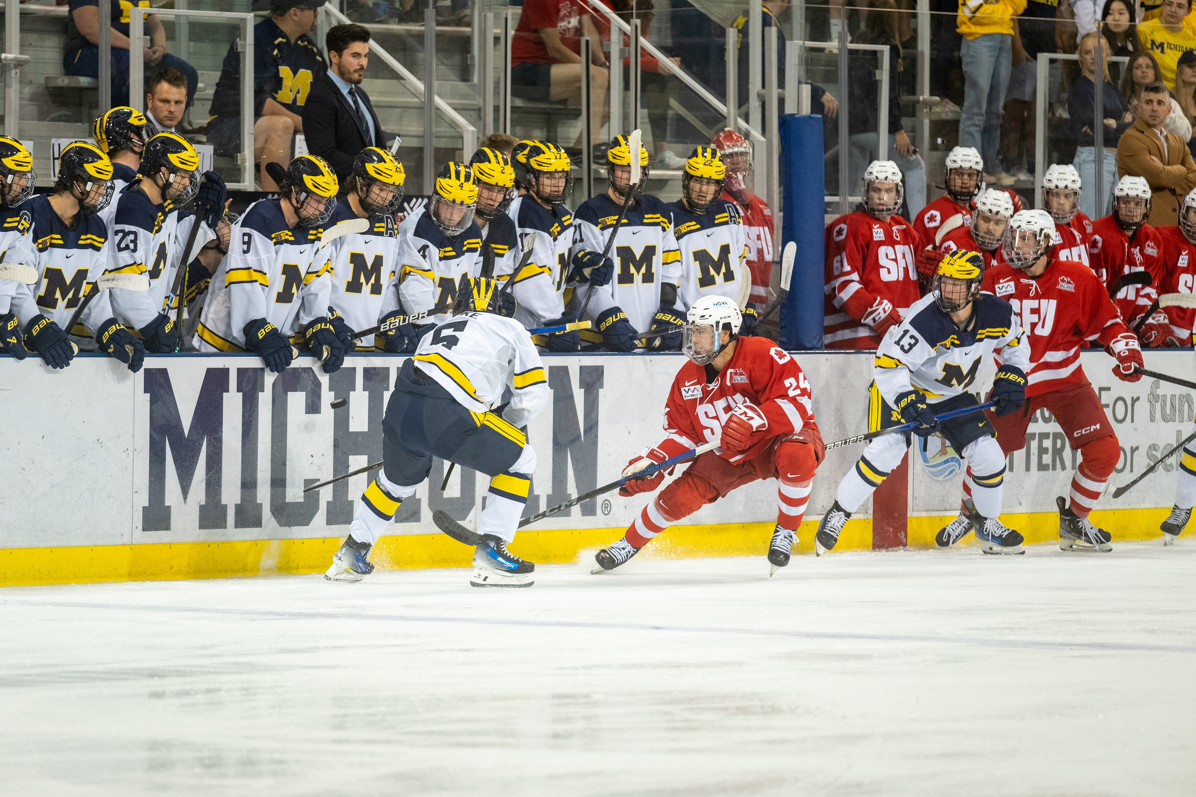 SFU at Michigan 09.30.23 | Forward Nick Wicks chips the puck along the boards past the defender.