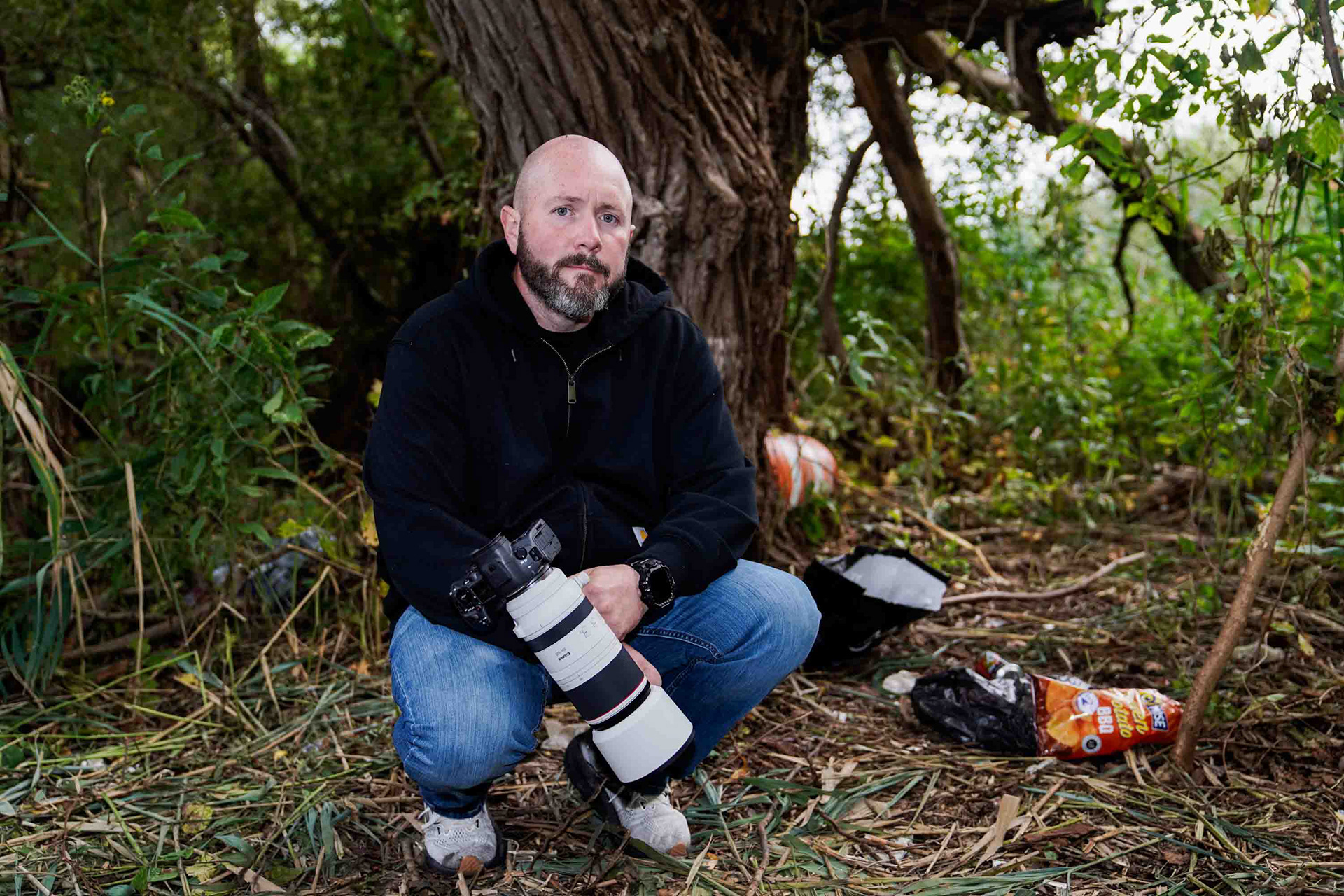 Wildlife photographer Dave Smith poses next to trash found by a homeless encampment on Murphy's Island on the south side of  Onondaga Lake in Syracuse, New York on Friday, October 3. Growing up in Liverpool, New York, Smith uses his newfound love for wildlife photography to share the environmental and community issues which still infect Onondaga Lake.