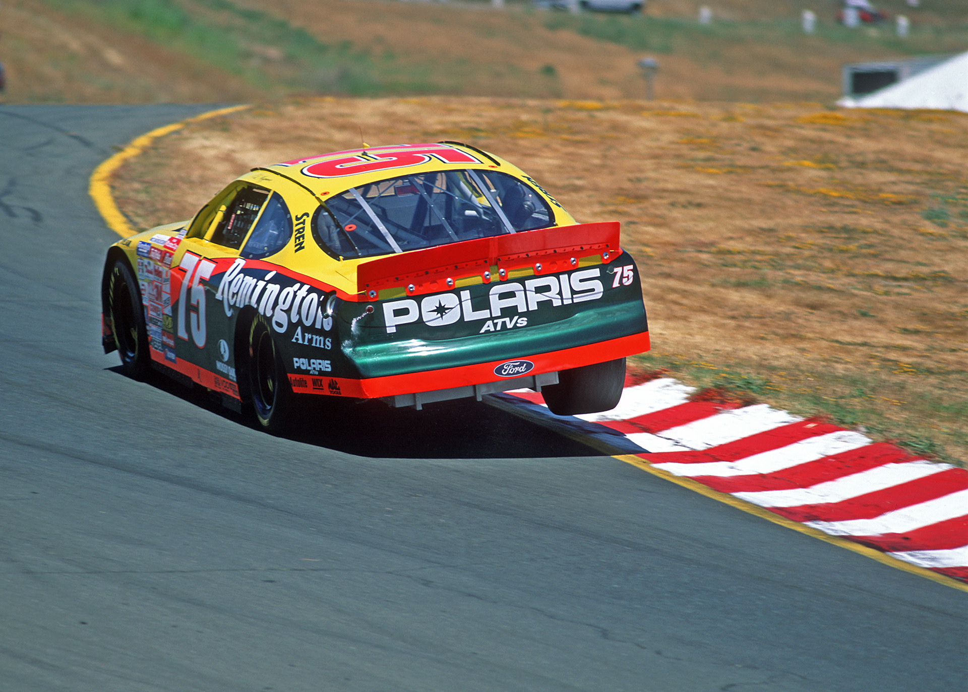1999 - Ted Musgrave in the Remington # 75 Ford Taurus - spills fuel from the breather and lifts the inside wheels in the old Turn 3 at Sears Point...  © IAN DONALD