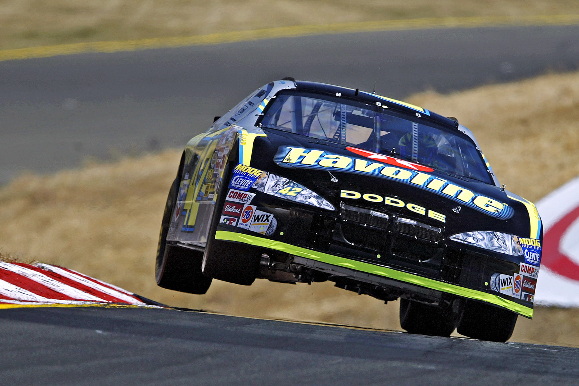 Ricky Rudd in the #42 Havoline car - the "Air Shot" . During the early 2000's redevelopment of Sears Point, the topography of the track was modified significantly to create new terraced spectator areas. Photographers lost their old vantage point which had enabled them to create the Track's signature "Air Shot" in Turn 3. Track Photographer Chucke Walkden worked out that if he positioned a Bucket Lift just above the top of the safety fence, our old viewpoint was restored... ©  IAN DONALD