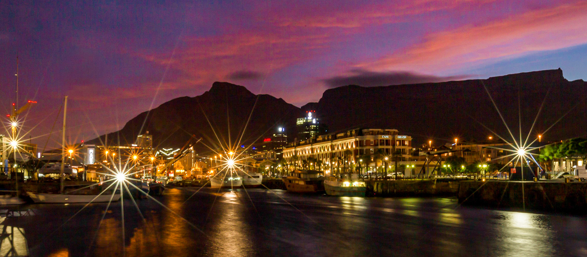 Sunset at the Victoria and Alfred Waterfront. The Victoria &amp; Alfred (V&amp;A) Waterfront in Cape Town has sweeping views of the Atlantic Ocean, Table Bay Harbour, the City of Cape Town and Table Mountain. Adrian van der Vyver has been credited with the design of the waterfront that is tourist friendly.  The Waterfront attracts more than 23 million visitors a year.