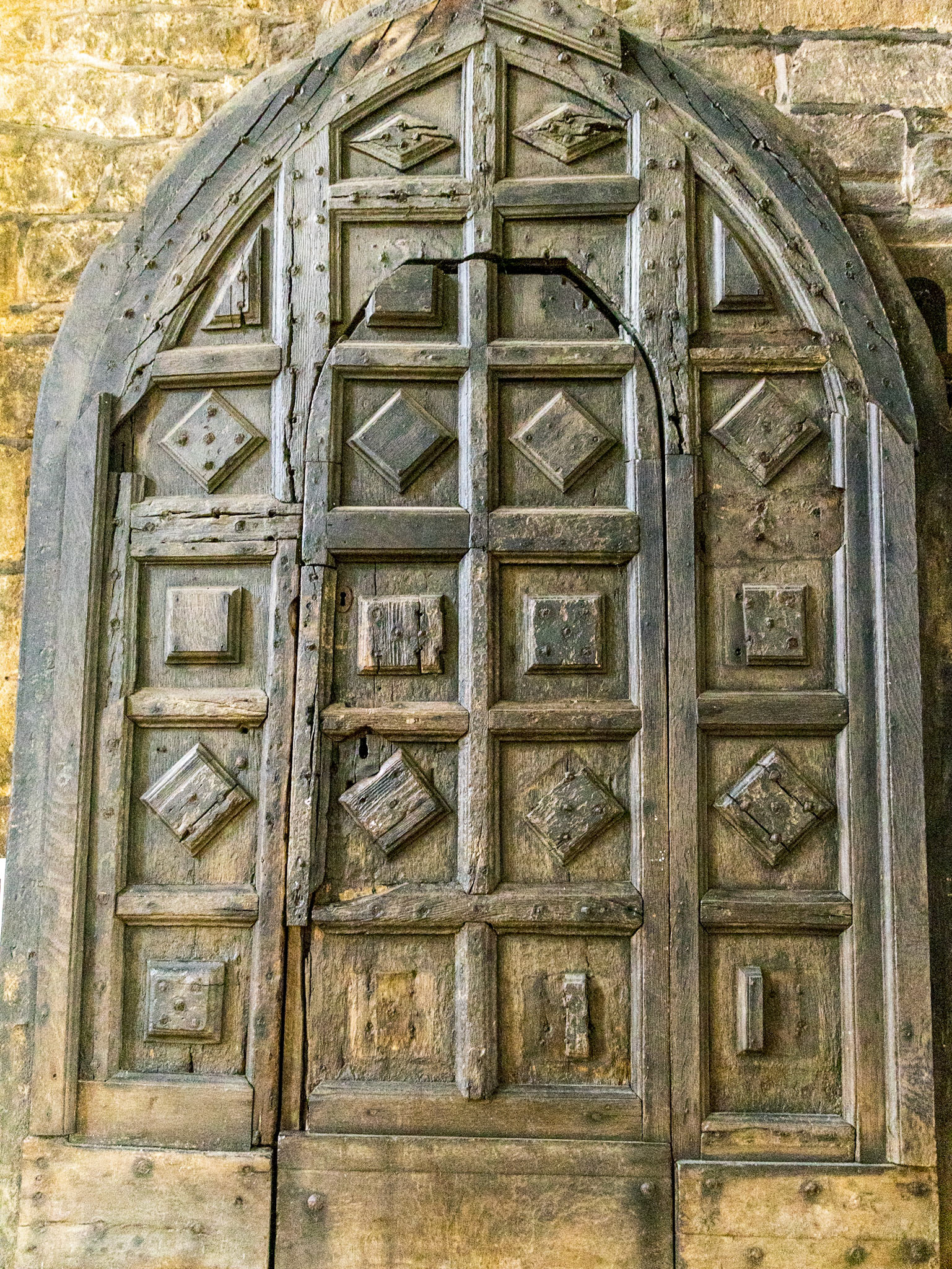 This old door is thought to have been made about 1500, constructed without mortice and tenon joints, by nailing sets of planks at right angles, the inner skin of horizontal planks, and the main outer skin of verticalplanks.The gaps between the edge of the planks are covered with decorative strips, making a third layer.There are also squares and diamond shapes covering some of the other nails. The many repairs over the years can be clearly seen.By 1997 much of the decoration was falling off as the rusting of the nails had split the wood. The bottom of the door, strengthened with additional planks, hadcome away from the rest of the door. The wicket in the main door had gaps above and beneath it, which were large enough to put a hand through.The Parish therefore proposed to replace the door, but preserve and display it withinthe building. Conservation bodies, including the Society for the Protection of Ancient Buildings, opposed this plan and argued for the door to be carefully restored. Havingheard evidence from both sides, including a number of experts, a church court approvedthe Parish's proposals.