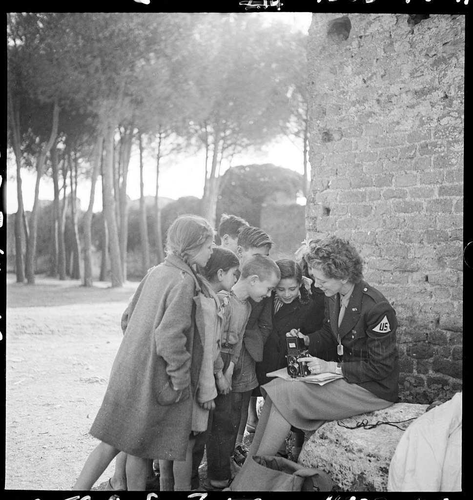 “Toni Frissell, sitting, holding camera on her lap, with several children standing around her, somewhere in Europe” 📷 Frissell, Toni, c. 1945  Original image from @librarycongress