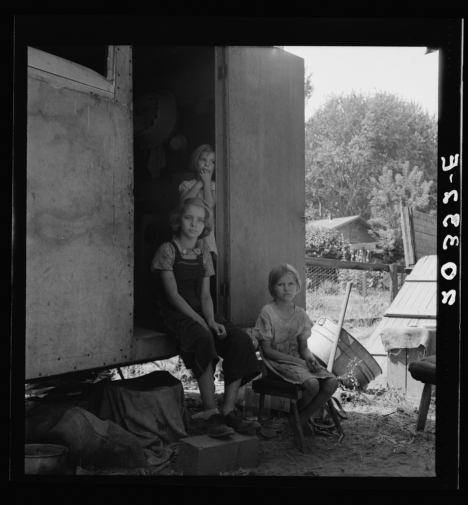 “The oldest girl seated in the doorway of the house trailer cares for the family. Yakima Valley, Washington” 📸 Dorothea Lange, 1939 Aug.  Original image from @librarycongress