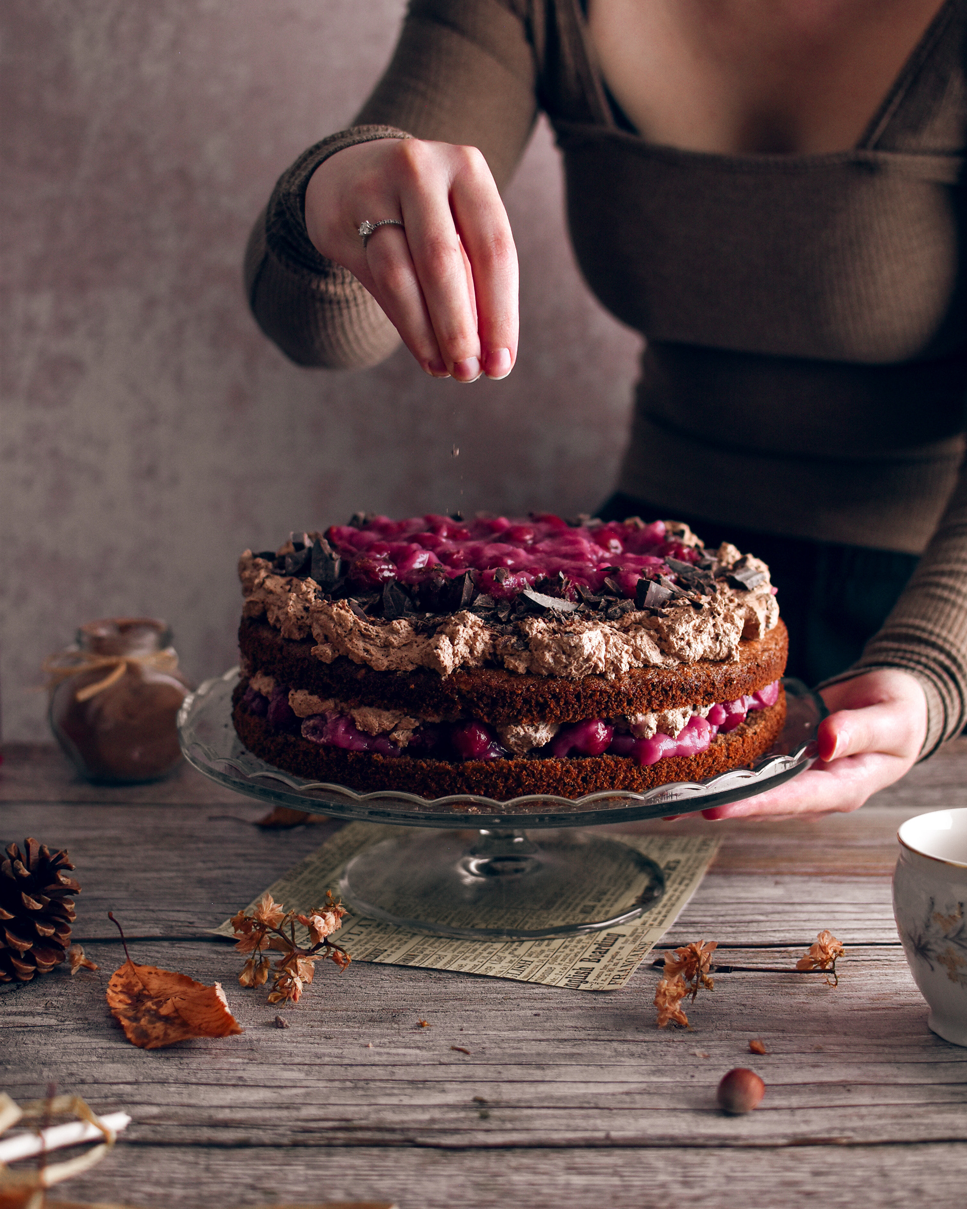 Woman sprinkling chocolate on the black forest cake 